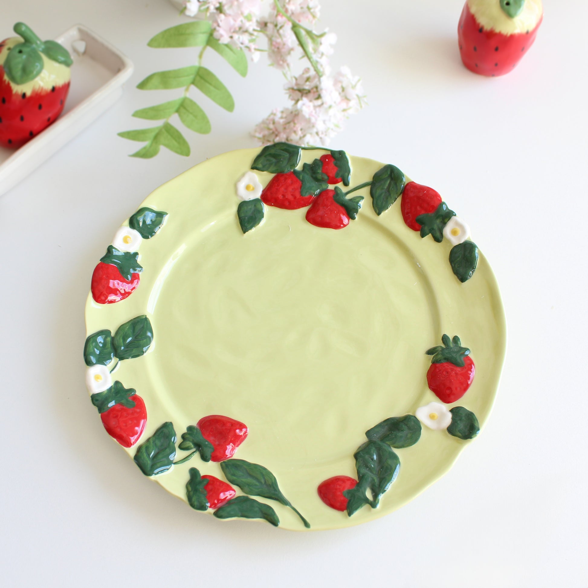 Detailed view of strawberry and floral embossed rim on handpainted stoneware dessert plate