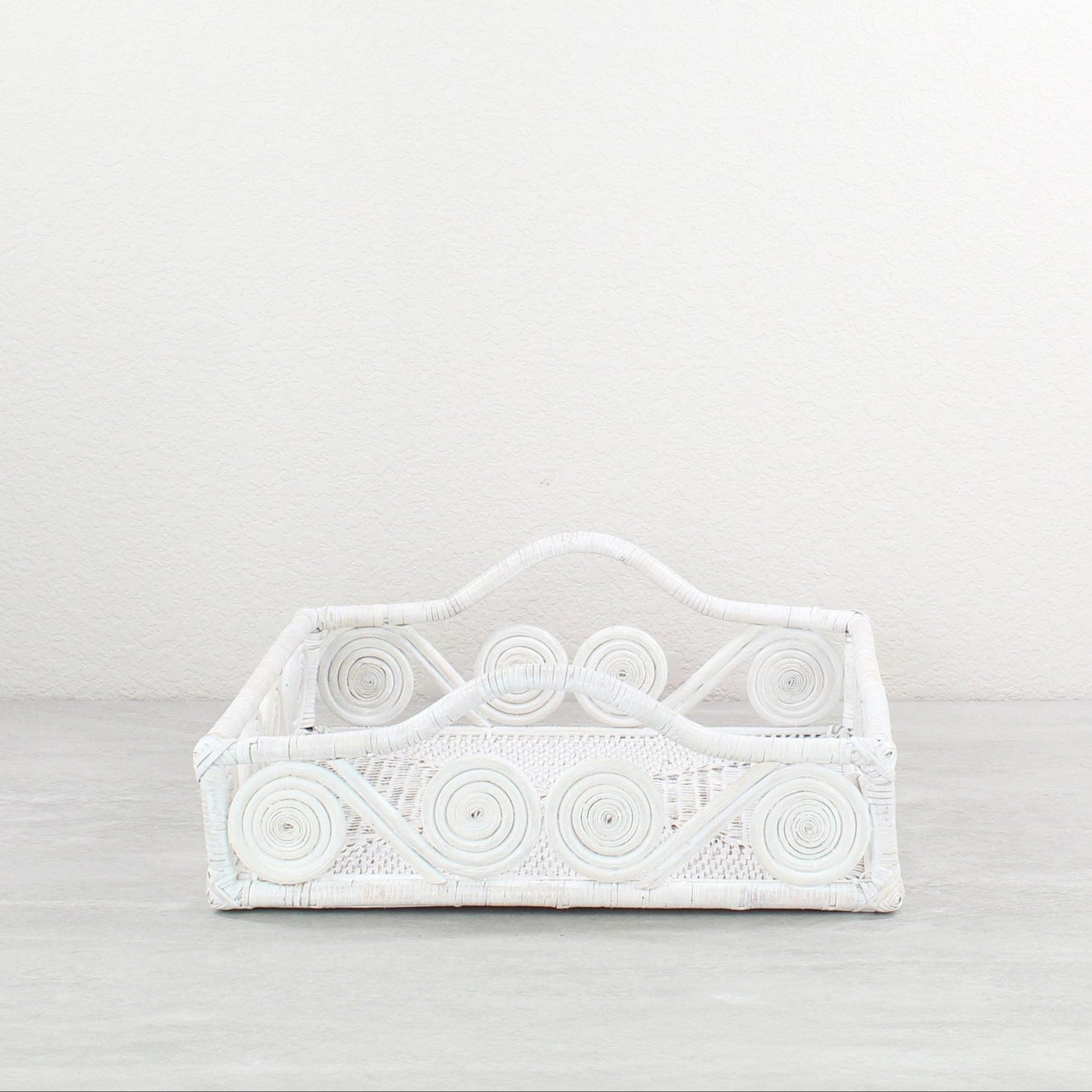 Whitewash decorative swirly rattan tray on a light gray background
