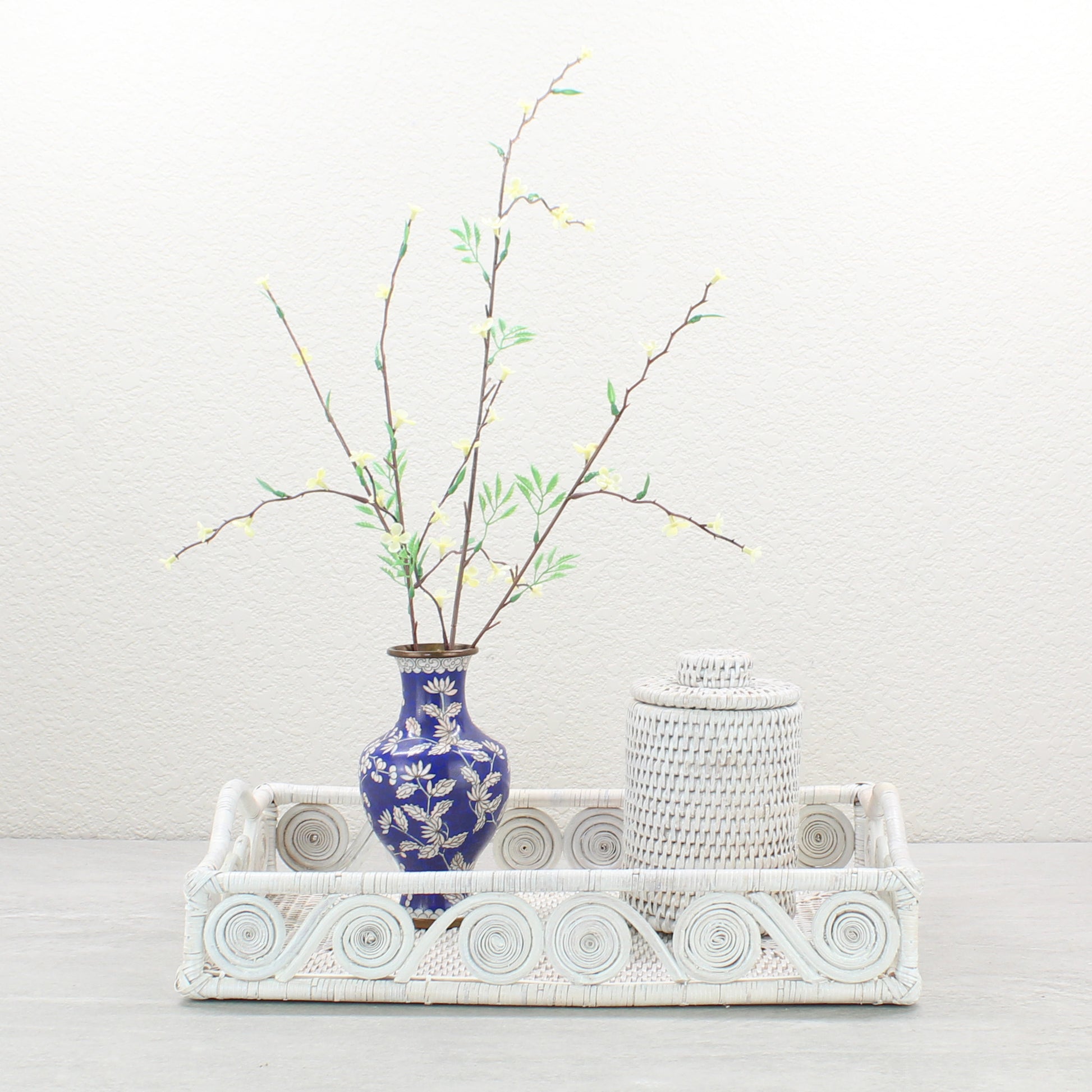 Whitewash rattan tray styled with a blue floral vase and matching lidded canister for elegant decorative display.