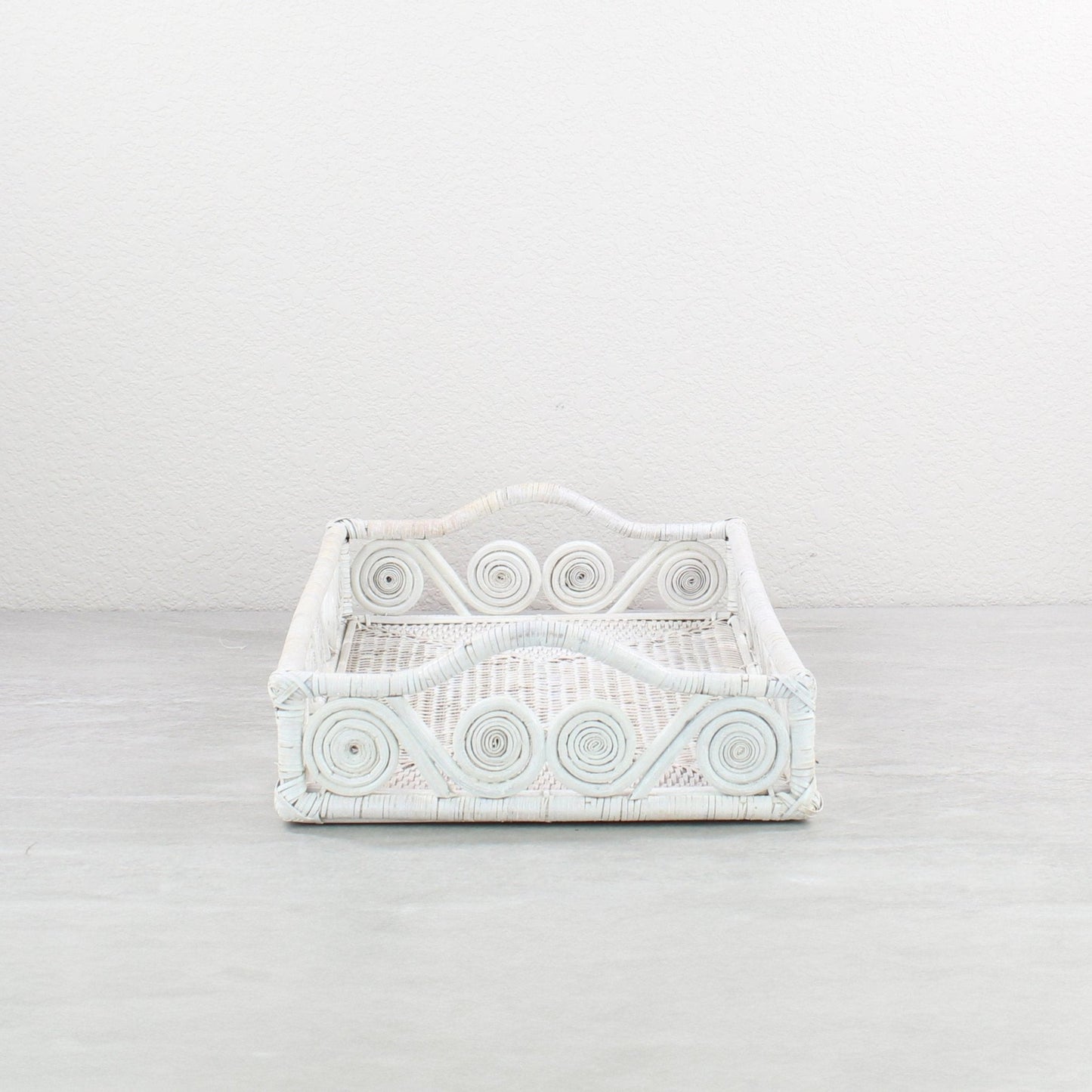 Close-up of swirly woven pattern on whitewash rattan tray, highlighting tight handwoven detail and curved edges.