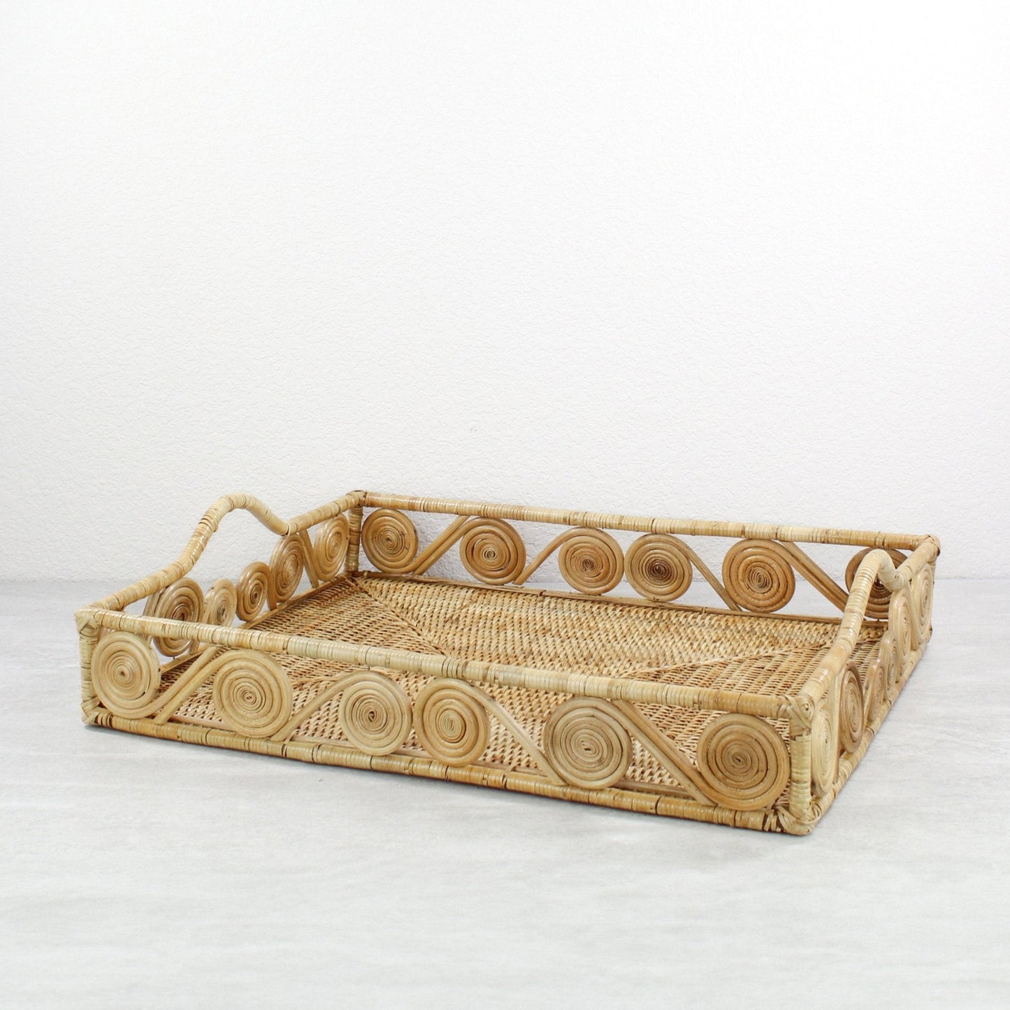 Empty natural rectangle rattan tray with swirl design and raised handles, handmade for serving or home décor.