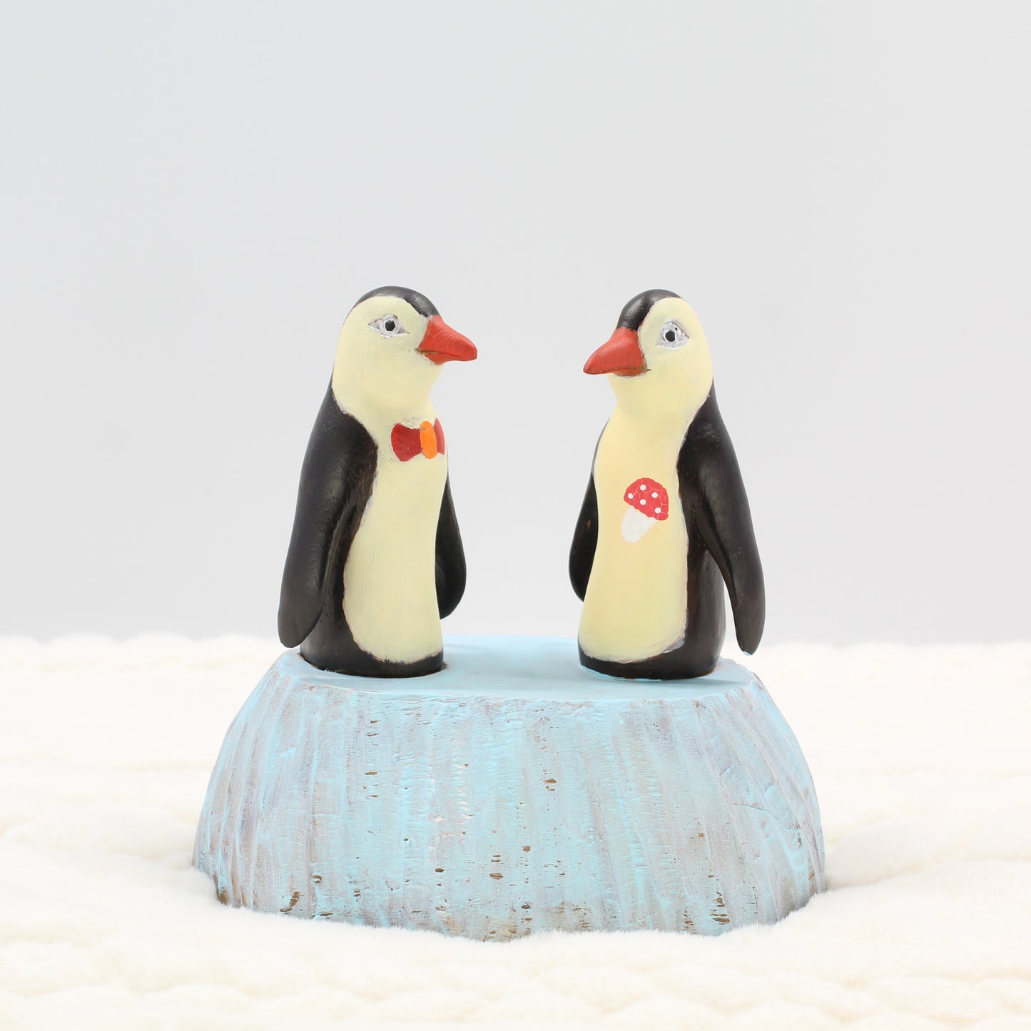 Pair of hand-painted wooden penguin sculptures with bow tie and mushroom detail, eco-conscious artisan décor figurines
