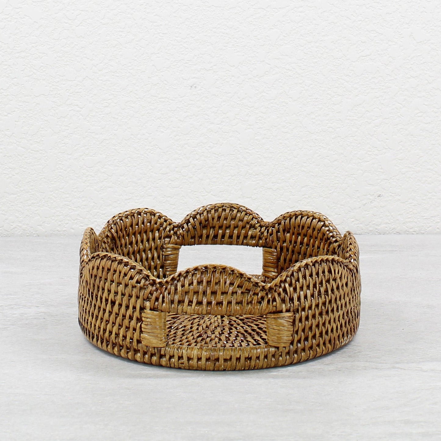 Small scalloped round rattan tray in honey brown with handles, handwoven eco-friendly storage and décor piece