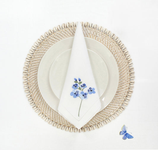Eco Handcraft round shell-trimmed rattan placemat with embroidered napkin styled on ivory ceramic plates