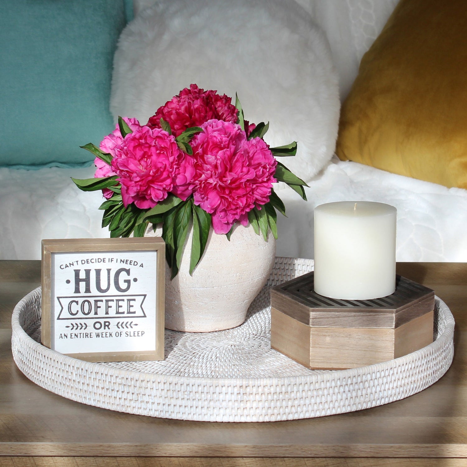 Sage green rattan tray, canister, and tissue box cover styled with flowers, books, and marble candles on a cozy modern coffee table.