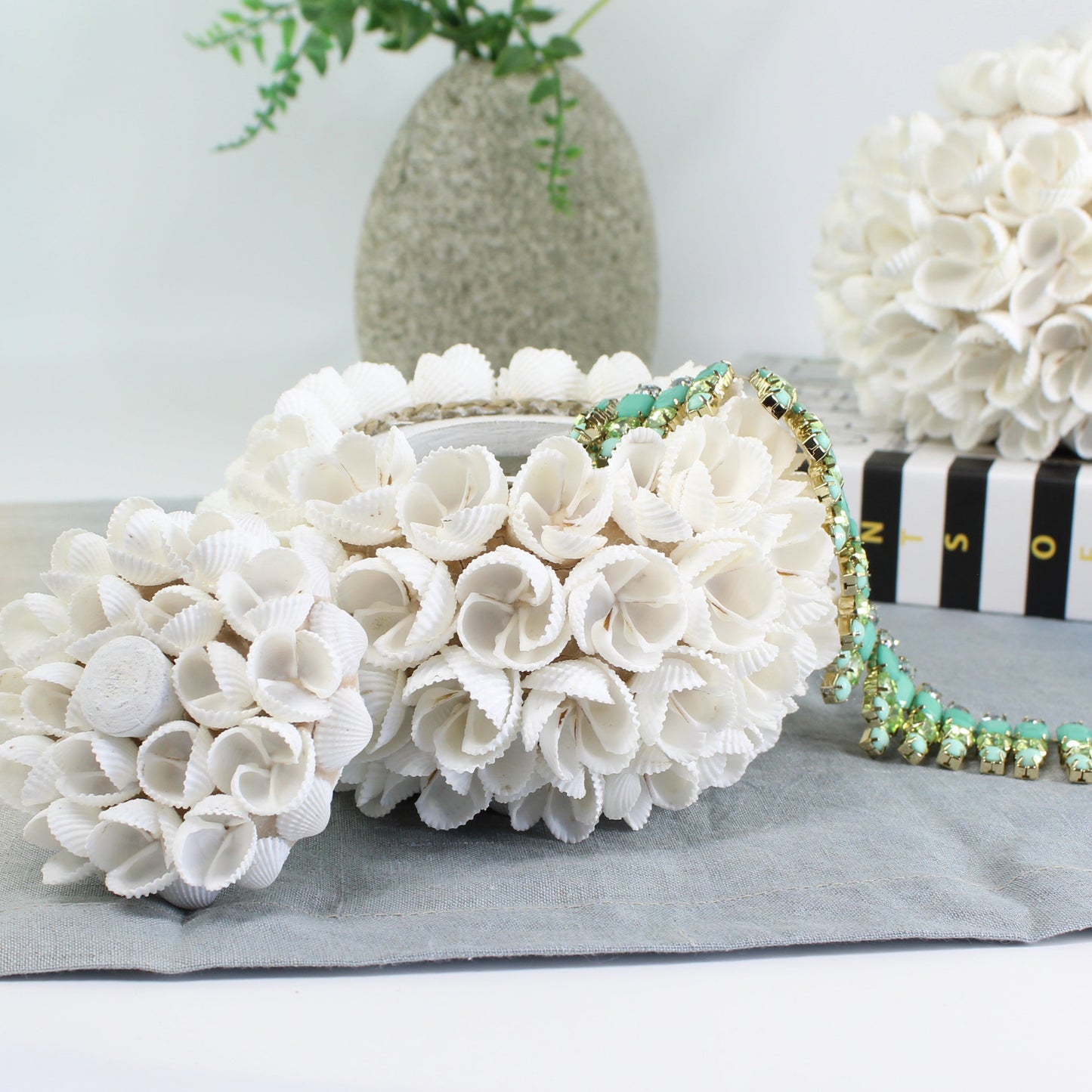 Medium seashell blossom jewelry box styled on a book with green floral necklace, handmade coastal decorative box for storage and gifting.