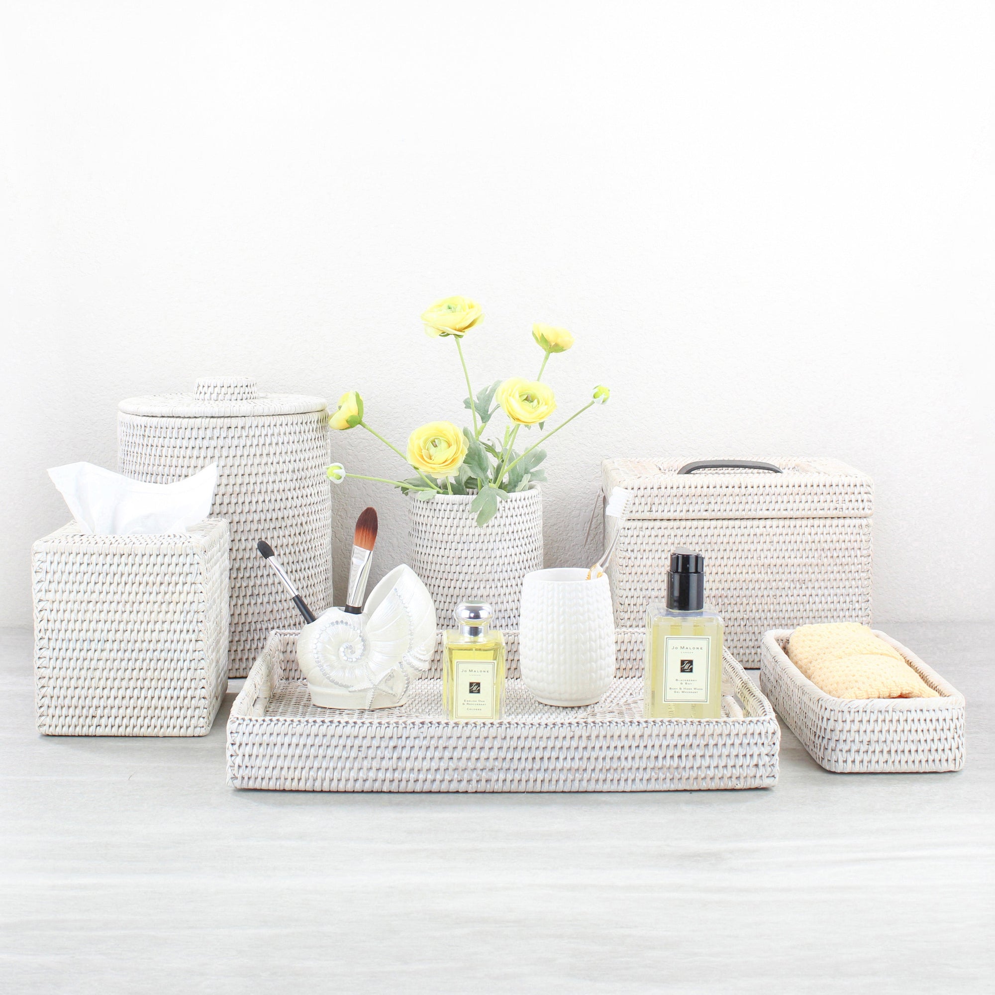 Eco Handcraft whitewash rattan bathroom tray and accessories styled with spa toiletries and flowers on a modern vanity