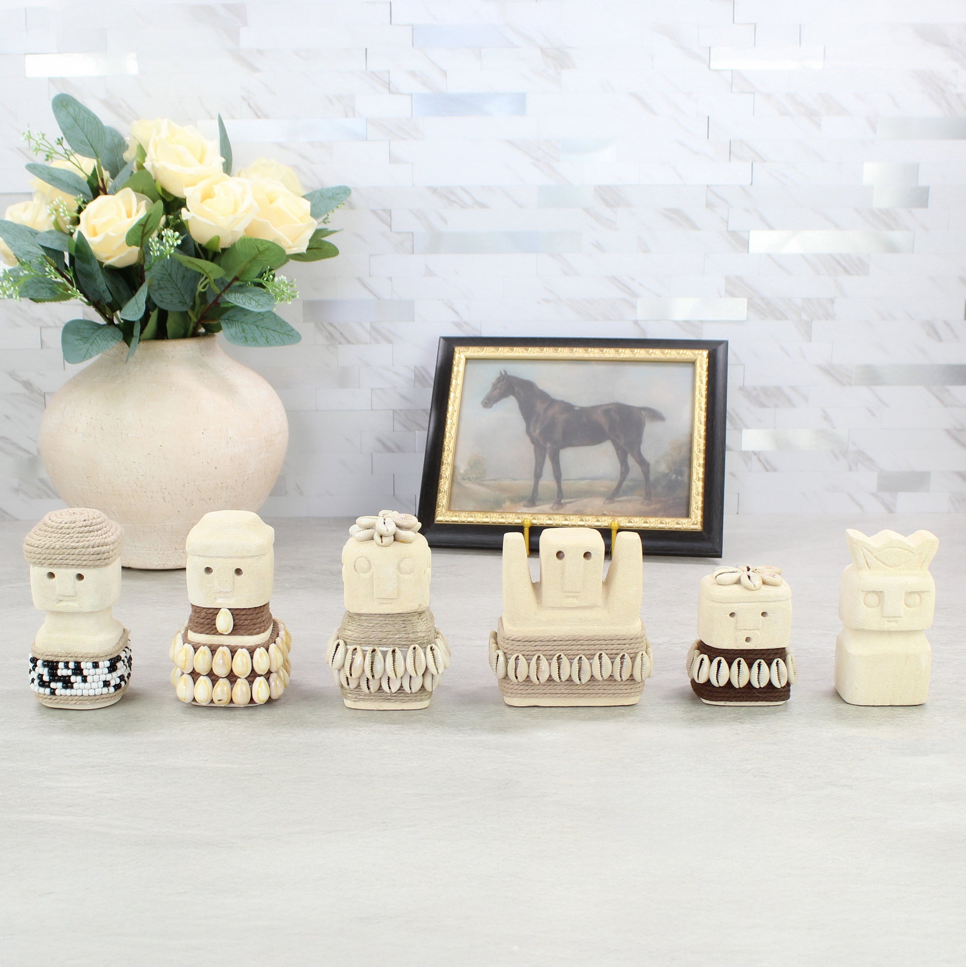 Handcrafted Sumba guardian figurine collection displayed on tabletop with vase and framed art — tribal coastal home decor.