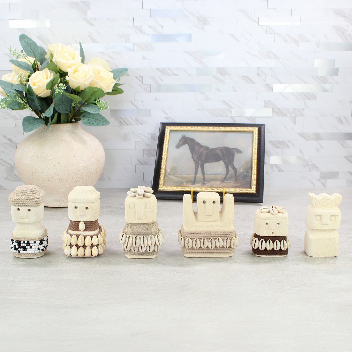 Handcrafted Sumba guardian figurine collection displayed on tabletop with vase and framed art — tribal coastal home decor.