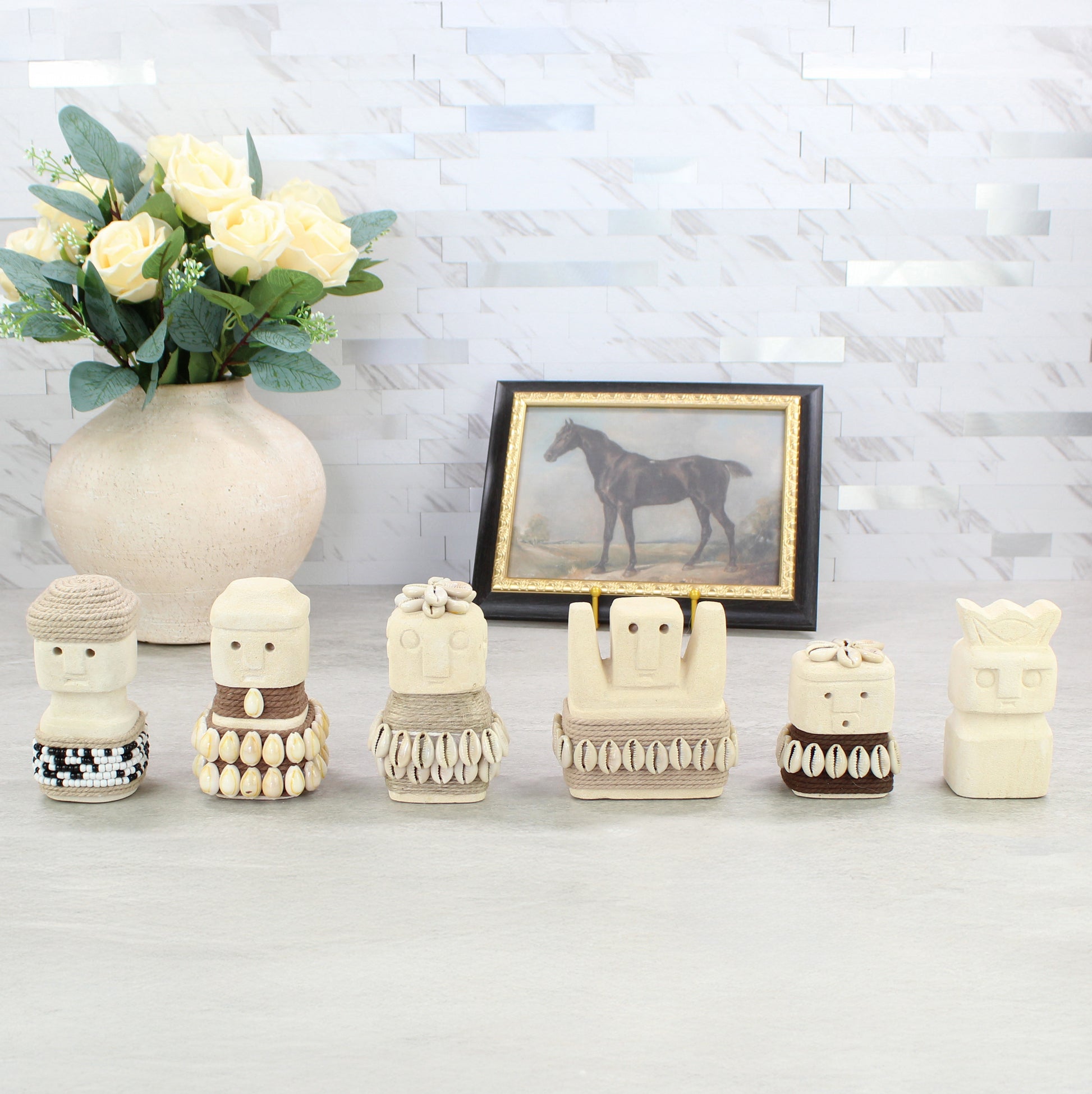 Handcrafted Sumba guardian figurine collection displayed on tabletop with vase and framed art — tribal coastal home decor.