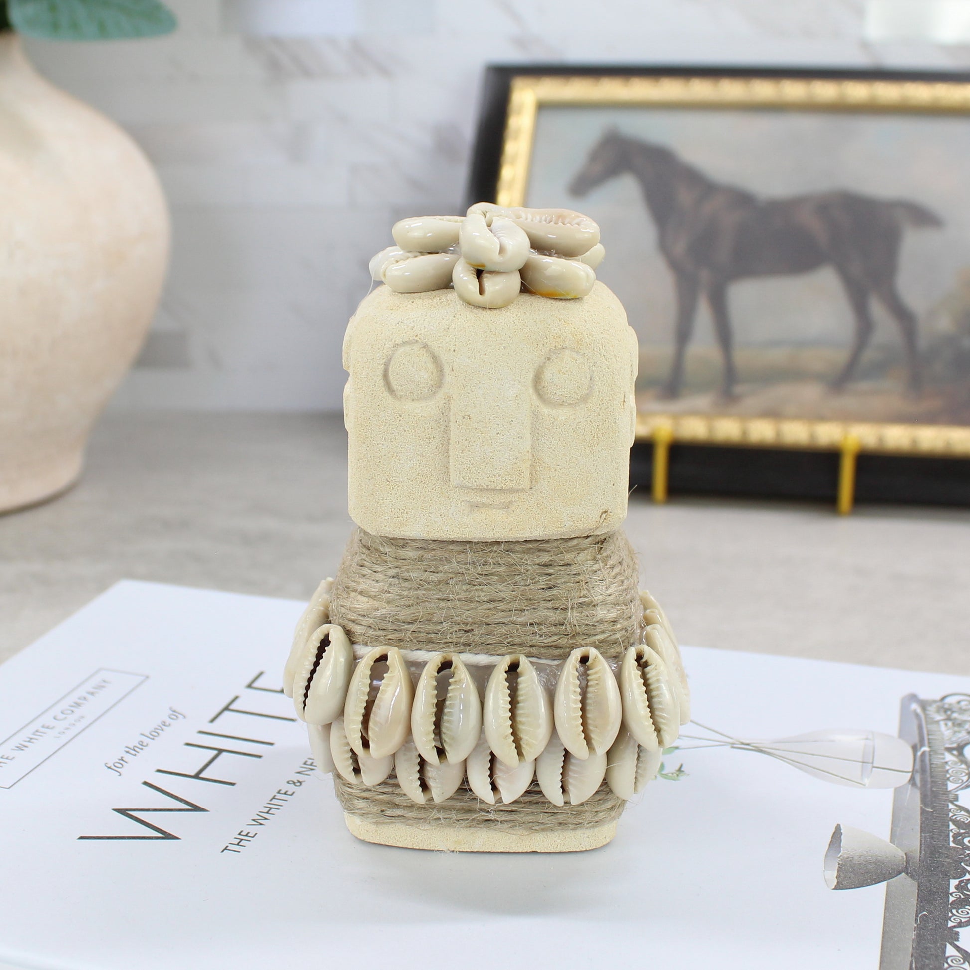 Handcrafted Sumba guardian figurine with flower crown and cowrie shell belt displayed on tabletop — handmade Balinese tribal home decor.