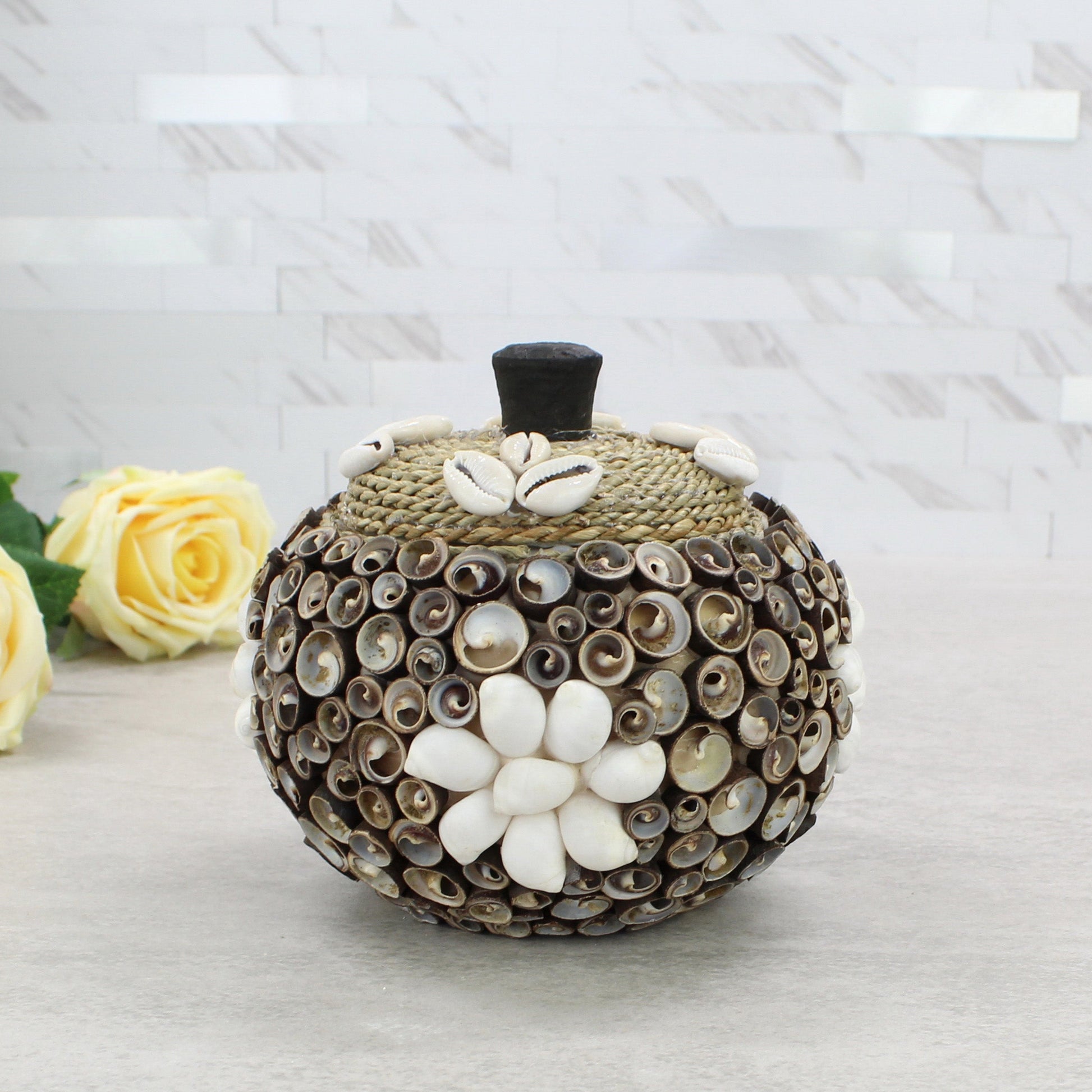 Large cowrie seashell storage box with rope lid, artisan handmade, styled with floral décor for coastal home or cottage display.