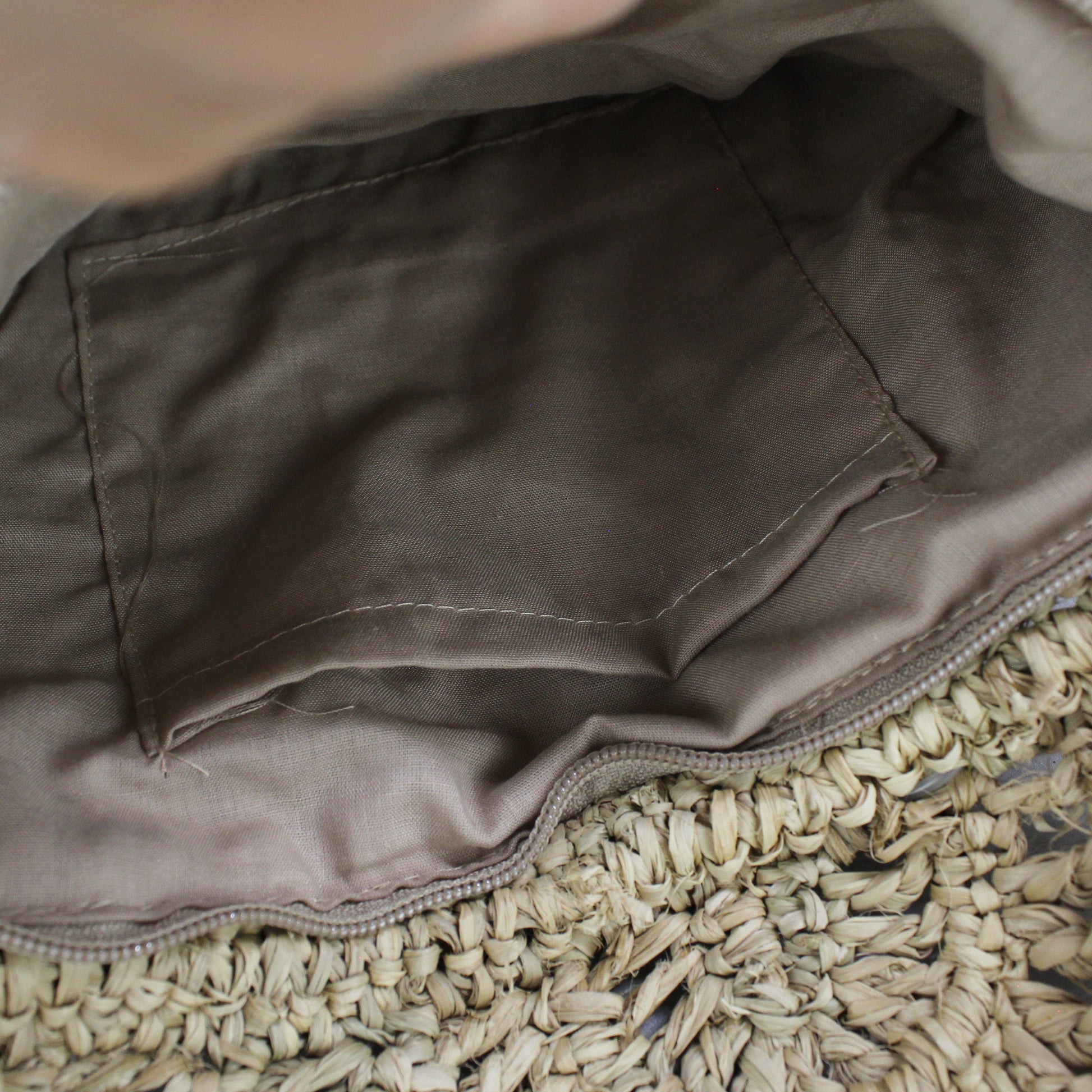 Interior view of raffia clutch with zip closure and fabric lining for secure and organized storage.