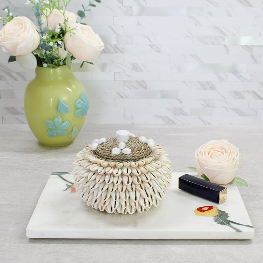 Handmade cowrie shell storage box styled with flowers and lipstick, ideal for vanity or dresser display.