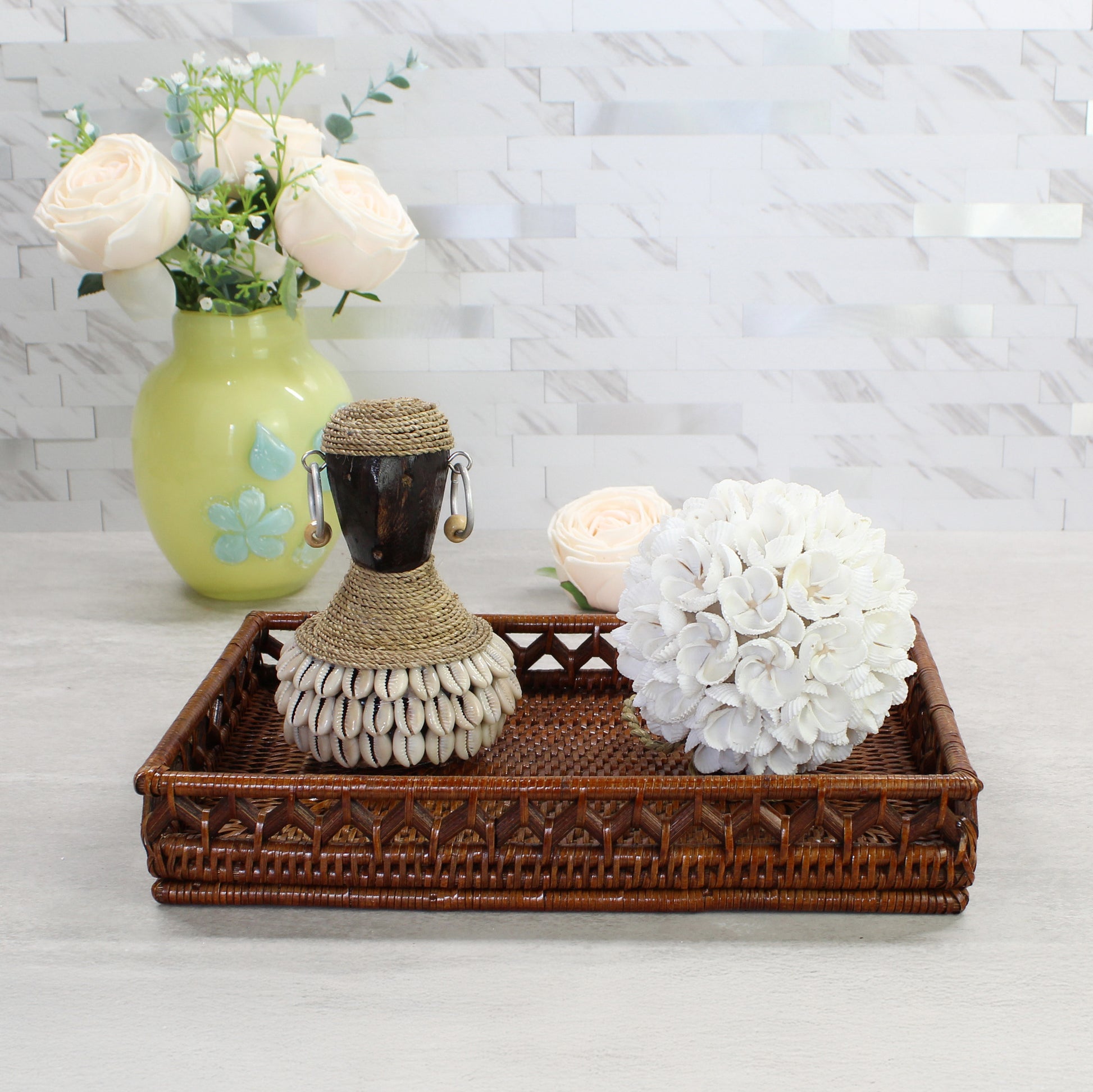 Handcrafted white seashell blossom ball displayed on a woven tray beside a Bali shell statue, showing artisan coastal craftsmanship and natural texture.