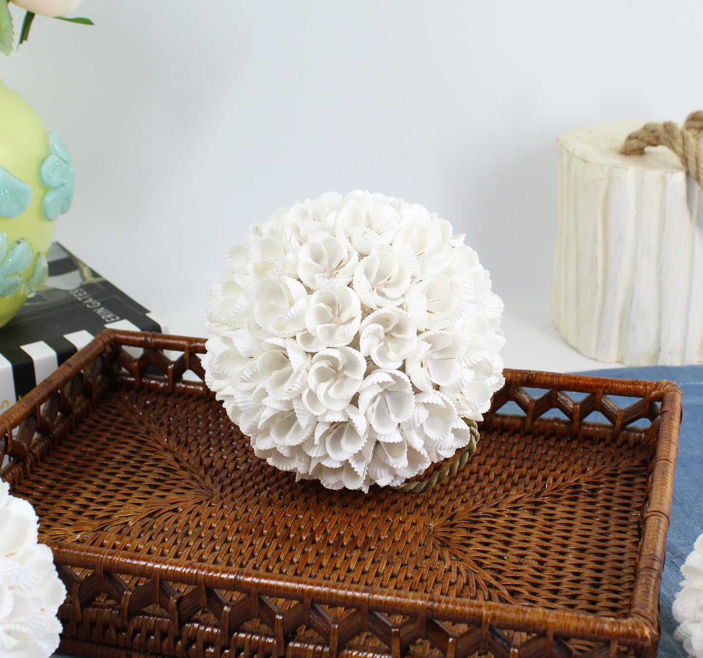Large handmade seashell blossom ball centerpiece made of layered white shells on a rattan tray, ideal for coastal or beach house décor styling.