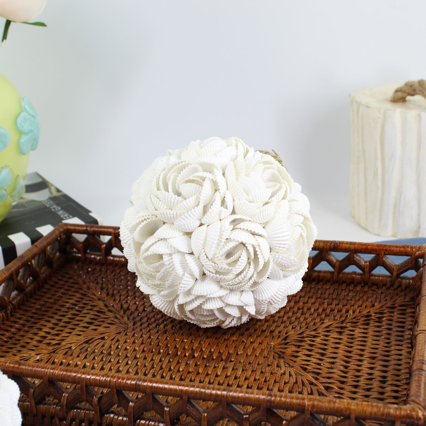 Large handmade seashell rose ball centerpiece made of layered white shells on a rattan tray, ideal for coastal or beach house décor styling.