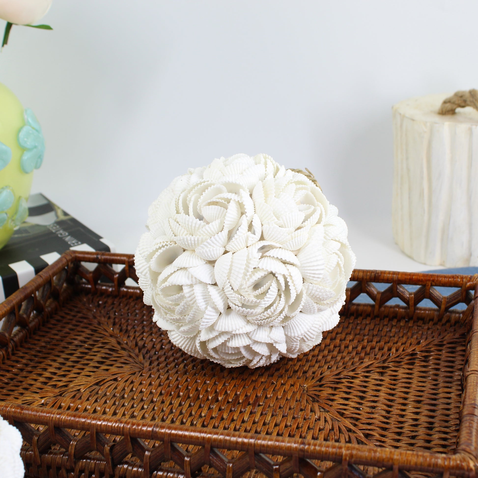 Large handmade seashell rose ball centerpiece made of layered white shells on a rattan tray, ideal for coastal or beach house décor styling.