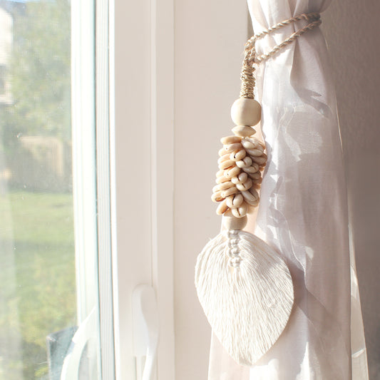 Handcrafted beige seashell tassel tied on sheer curtain near window for coastal home décor accent