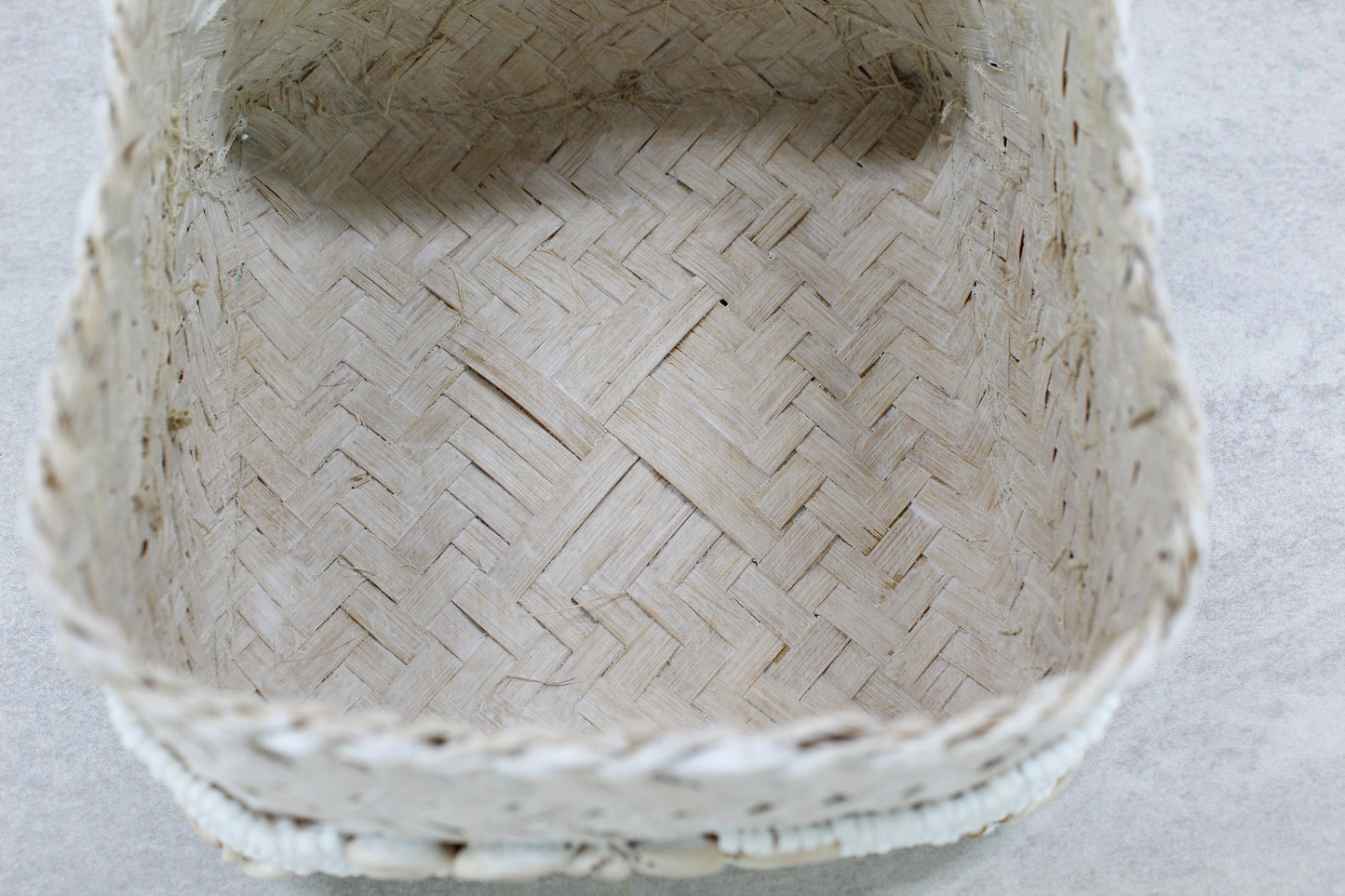 Interior of handmade beaded cowrie shell box showing woven natural bamboo base and handcrafted details.