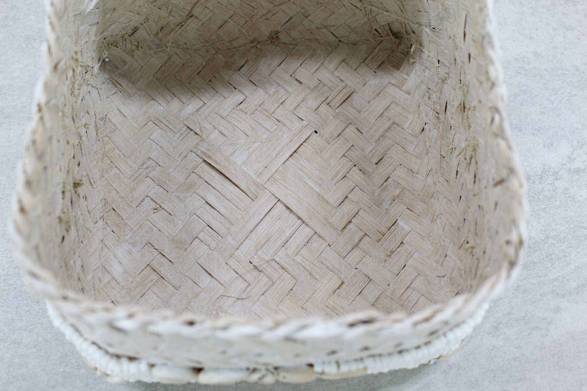 Interior of handmade beaded cowrie shell box showing woven natural bamboo base and handcrafted details.