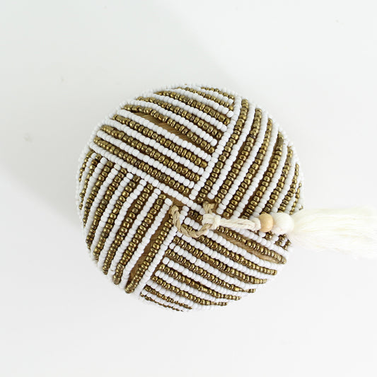 Top view of round bamboo jewelry box with white and gold bead linear pattern and tassel detail