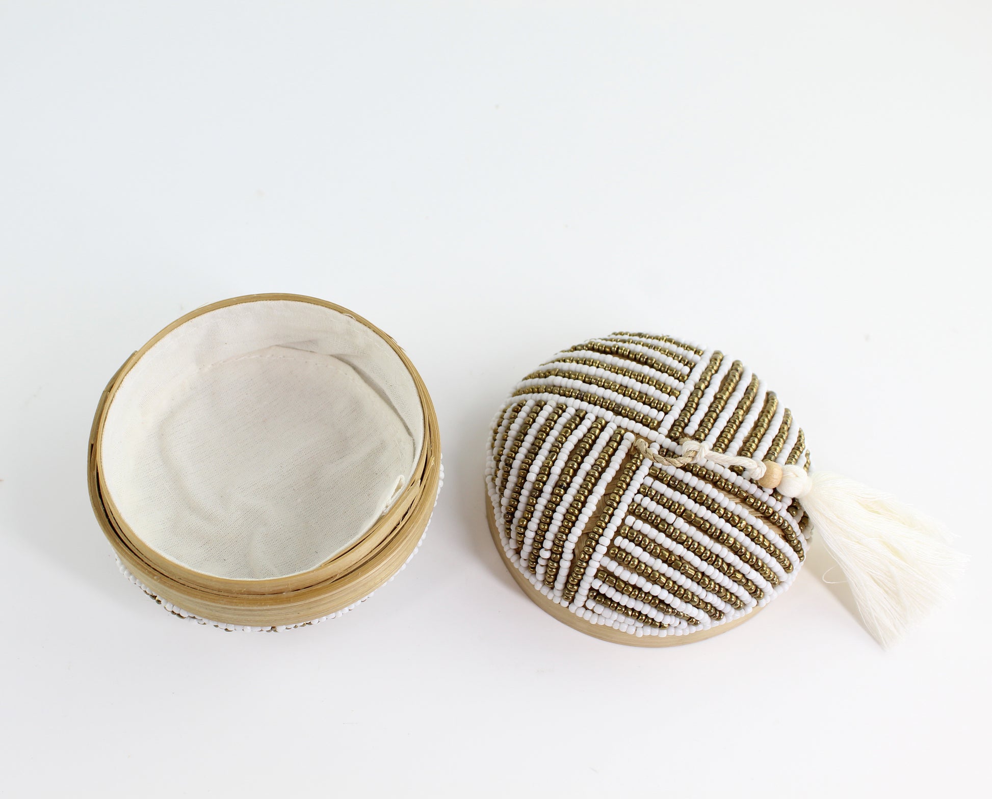 Open handmade white and gold linear beaded bamboo tassel box showing fabric-lined interior