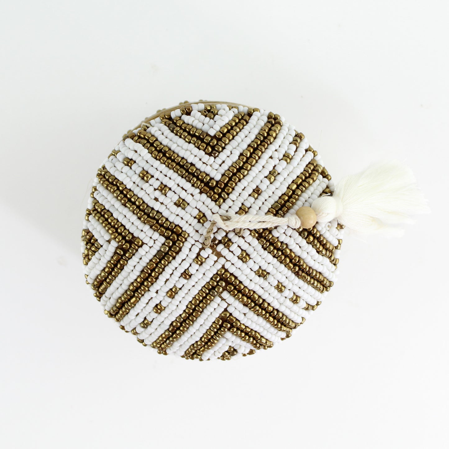 Top view of handmade white and gold chevron beaded bamboo tassel box highlighting intricate beadwork and artisan craftsmanship.