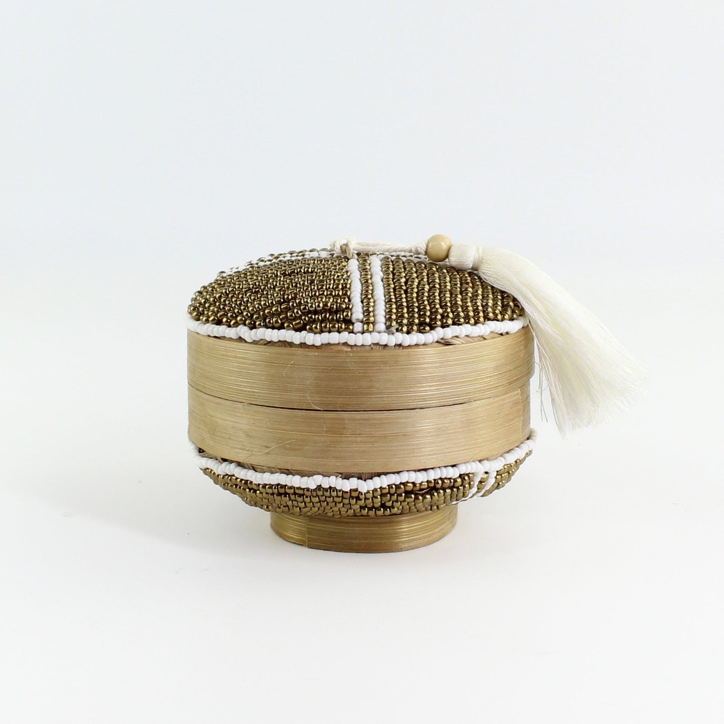 Side view of handmade white and gold beaded bamboo tassel box with ivory tassel highlighting artisan texture and craftsmanship.