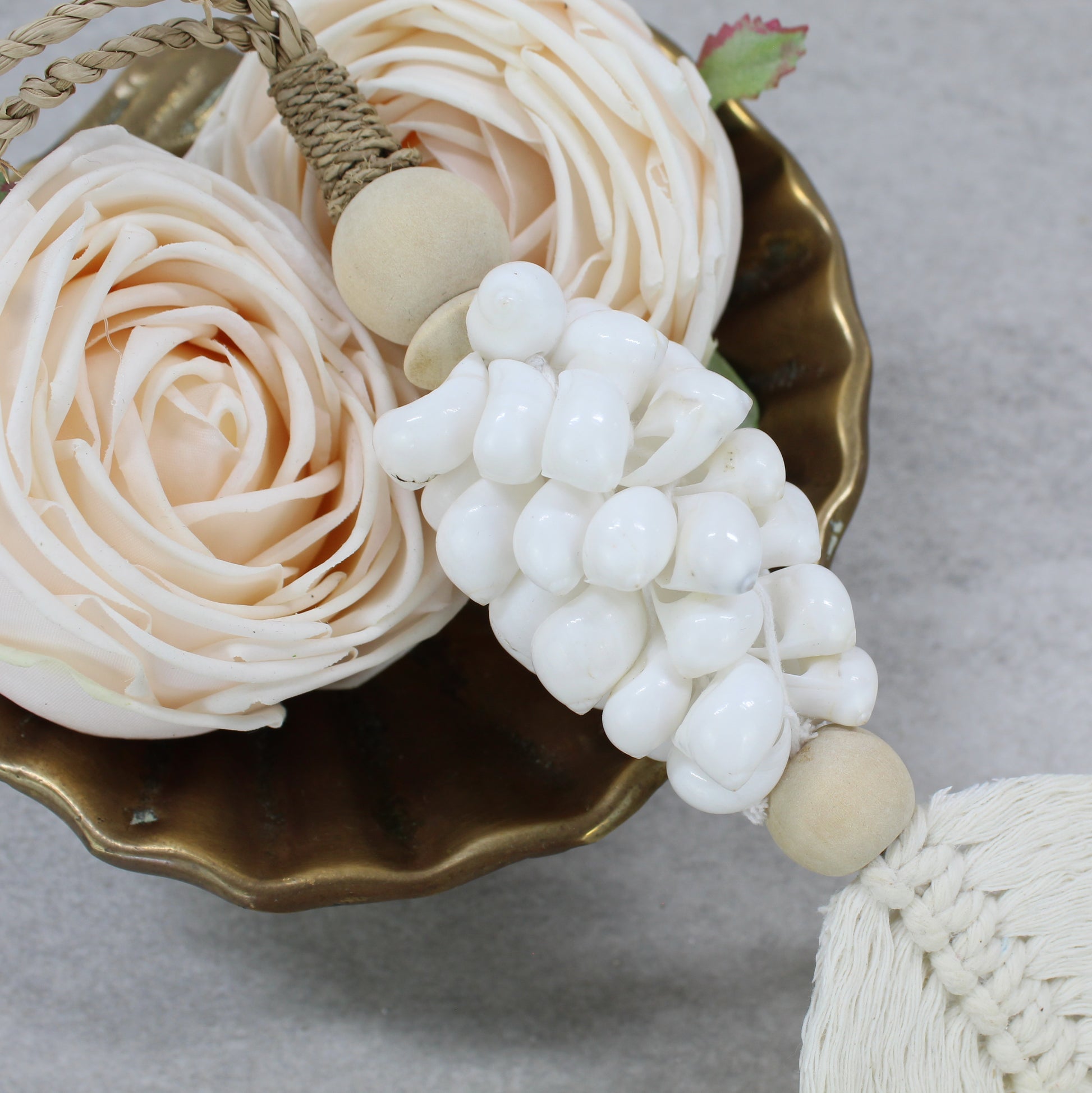 Close-up of white shell tassel handmade with natural jute rope, wood beads, and cotton fringe leaf detail