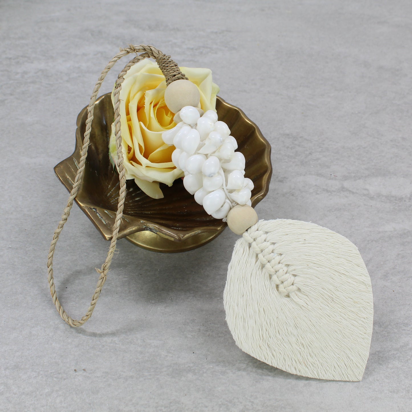 Handmade white shell tassel with macramé cotton leaf and jute hanger styled with yellow rose in bowl decor setup