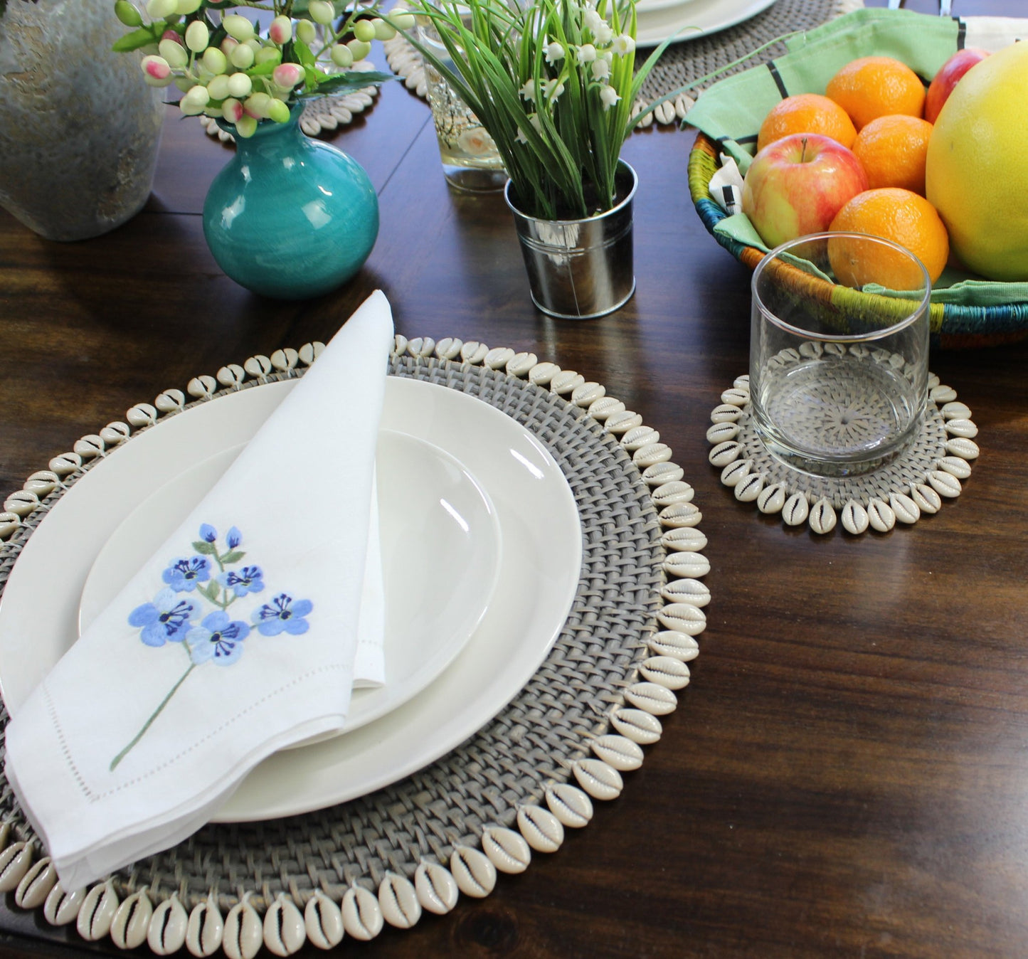 Grey eco-friendly rattan coasters styled in coastal home with candles, flowers, and tropical table décor