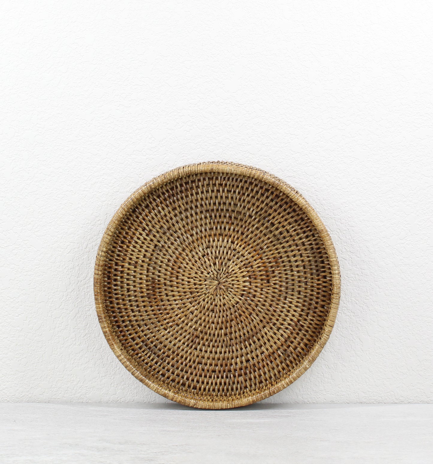 Eco Handcraft small honey brown round rattan tray, tightly woven artisanal design, sustainable décor piece for serving or organizing.