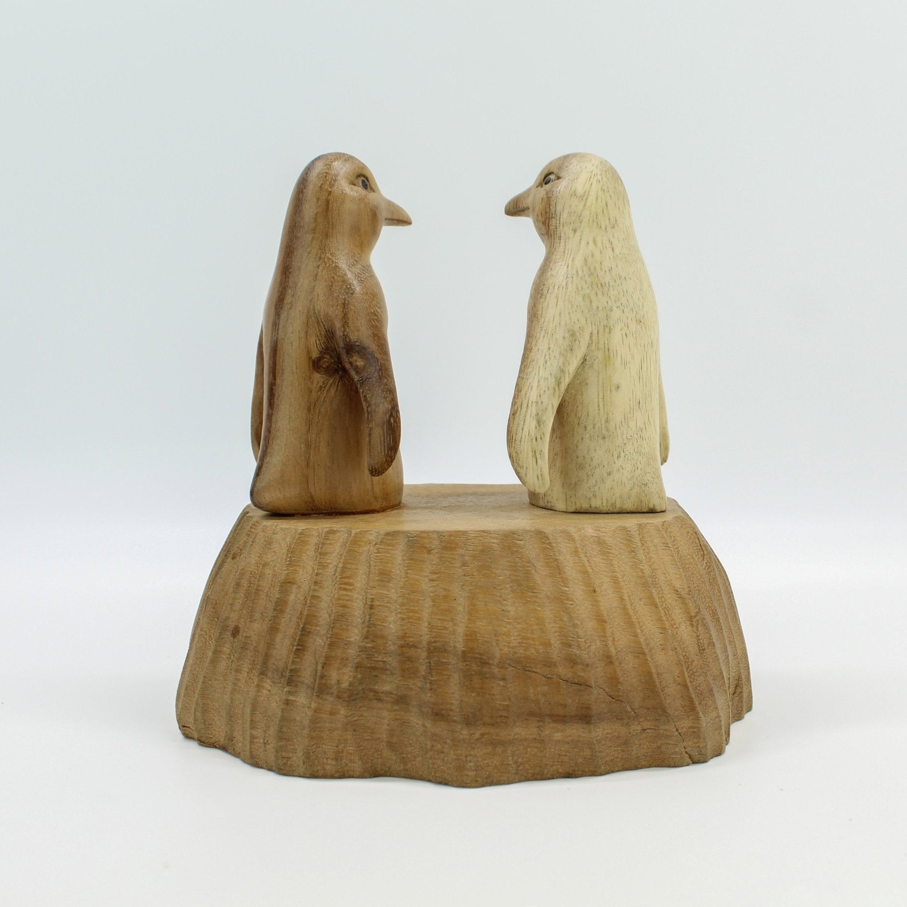 Eco-friendly hand-carved wooden penguin figurines on a wooden base, perfect Christmas or housewarming gift décor.
