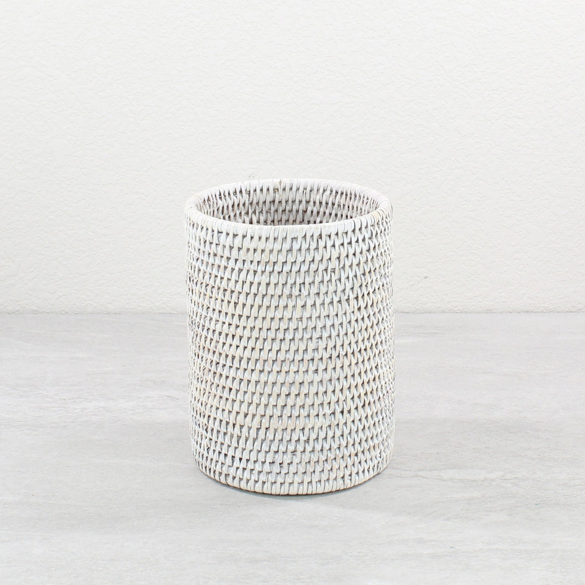 Whitewash rattan wine bottle holder on a light surface.