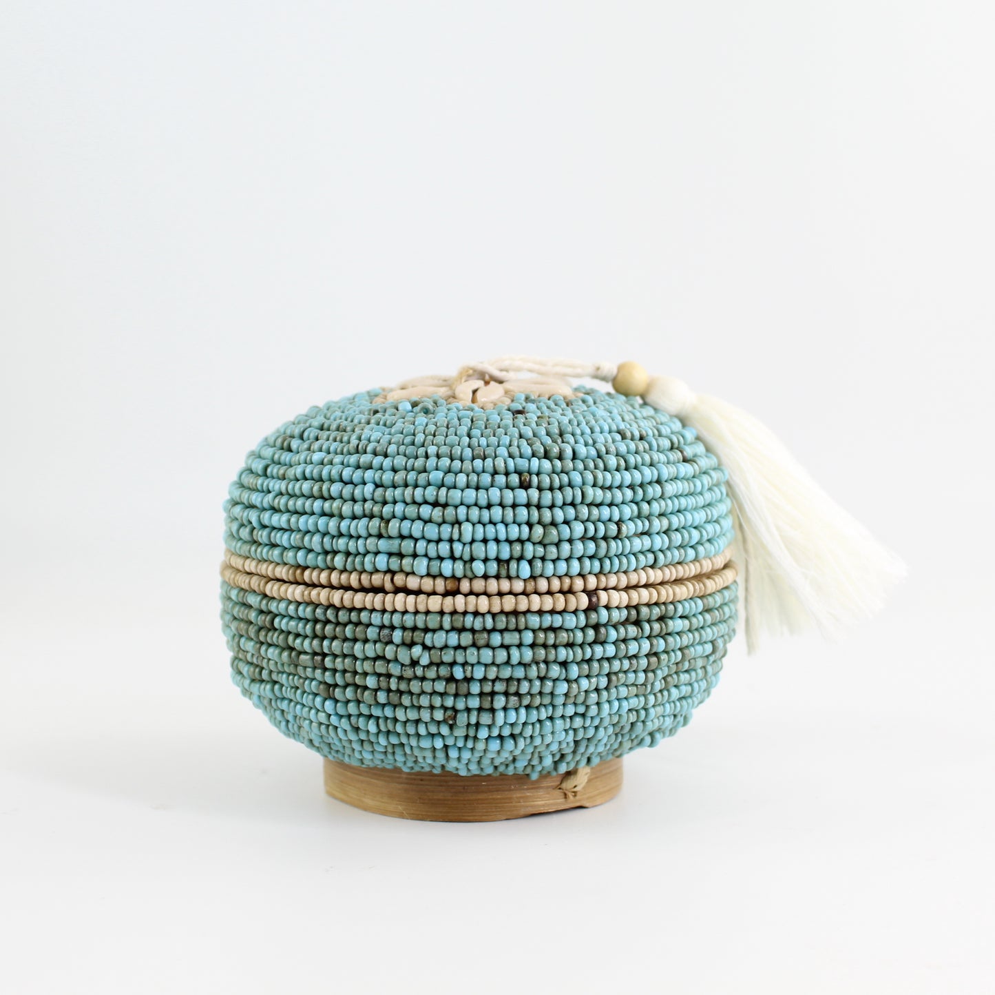 Round turquoise beaded storage box with cowrie shell flower and tassel, handmade coastal jewelry box.