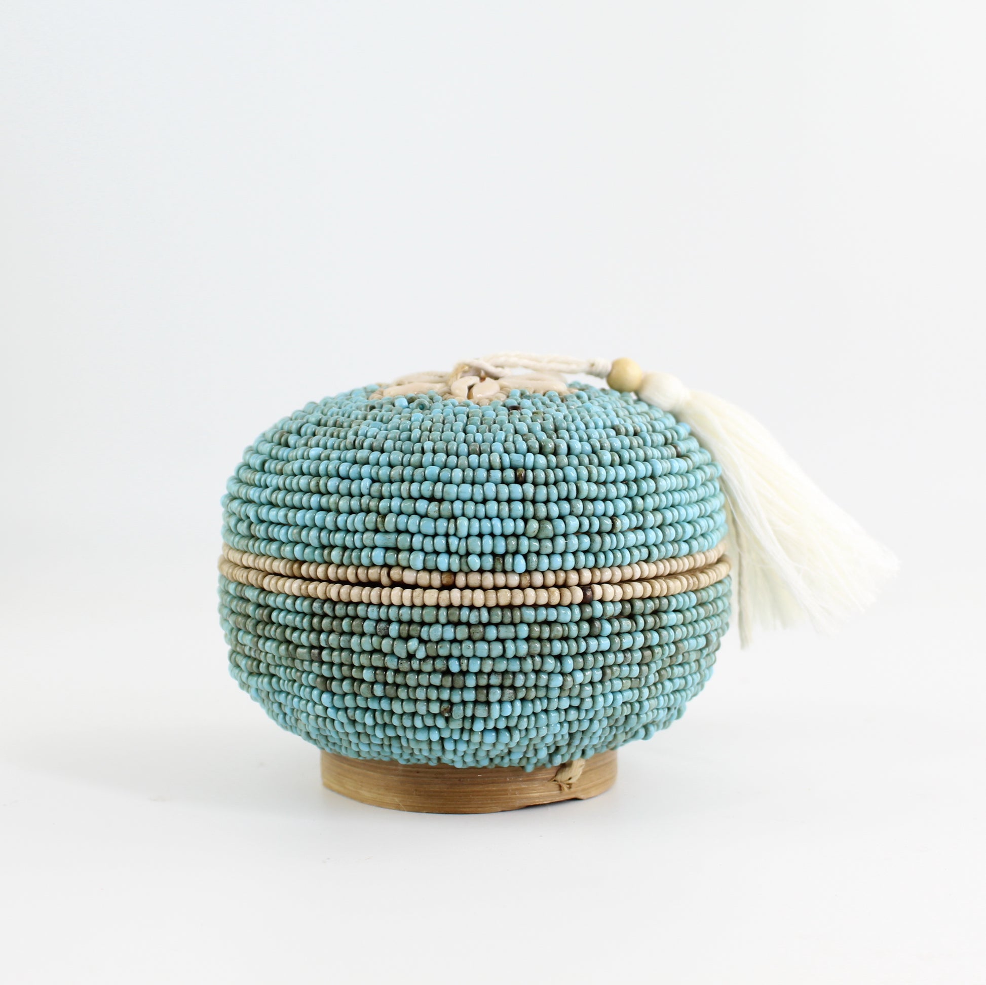 Round turquoise beaded storage box with cowrie shell flower and tassel, handmade coastal jewelry box.