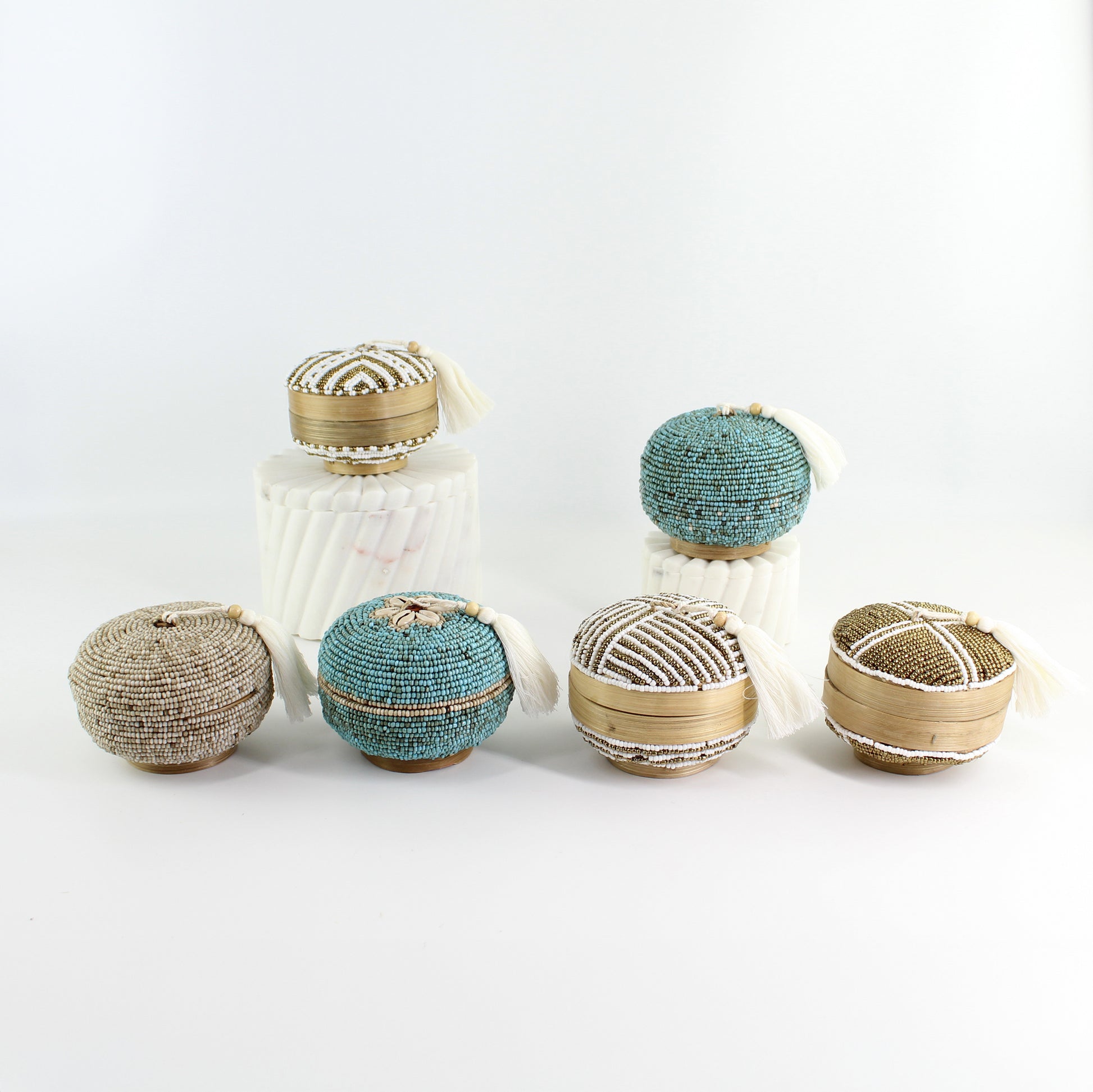 Eco Handcraft round beaded tassel box collection in turquoise, white, and gold tones styled for coastal home décor