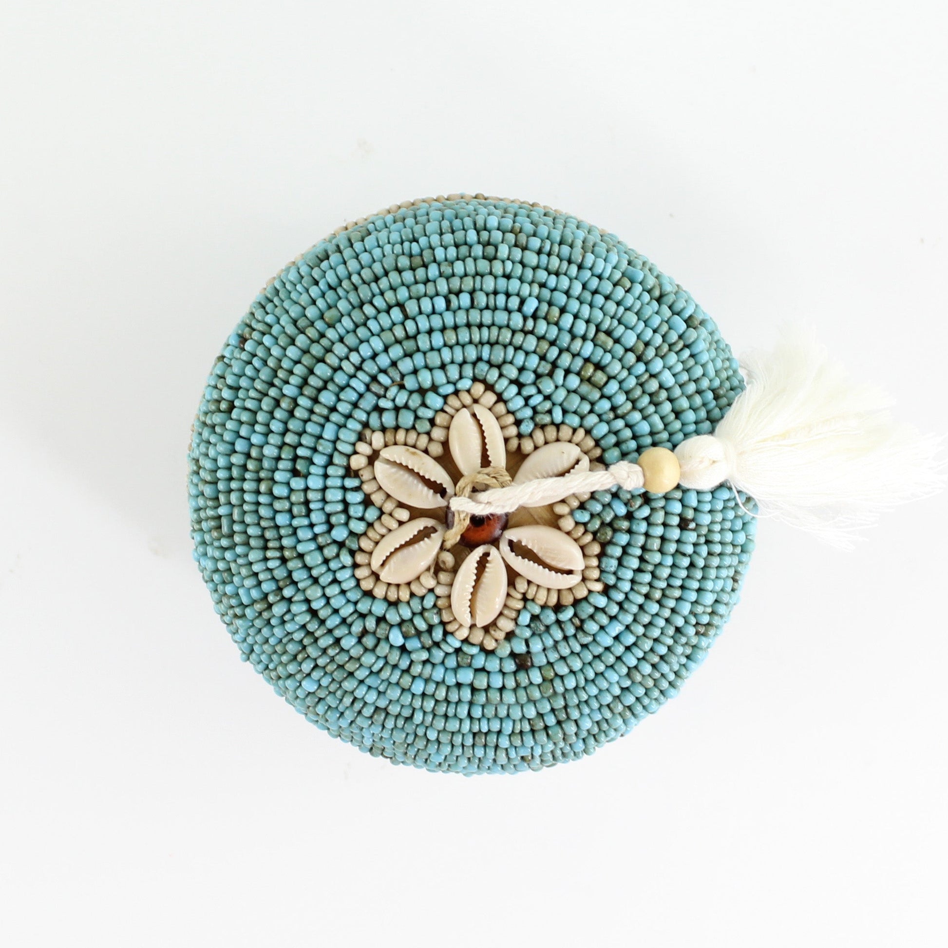 Top view of handmade turquoise beaded box showing cowrie shell flower design and ivory tassel accent.