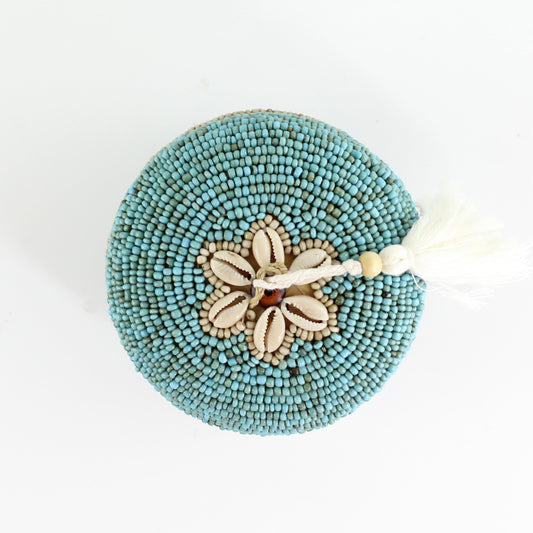 Top view of handmade turquoise beaded box showing cowrie shell flower design and ivory tassel accent.