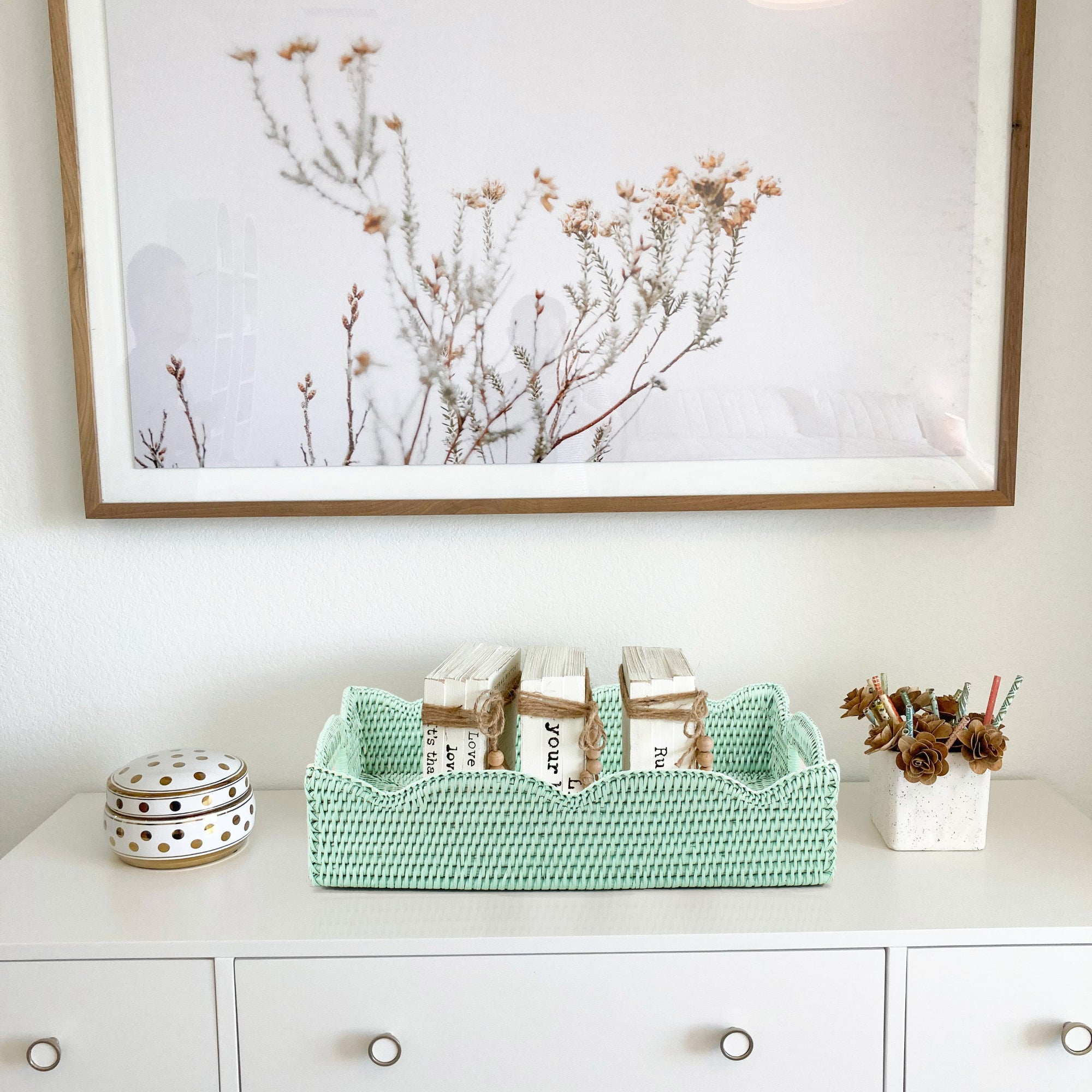 Eco Handcraft sage green scalloped rattan tray styled on an entryway dresser with books and decor accents
