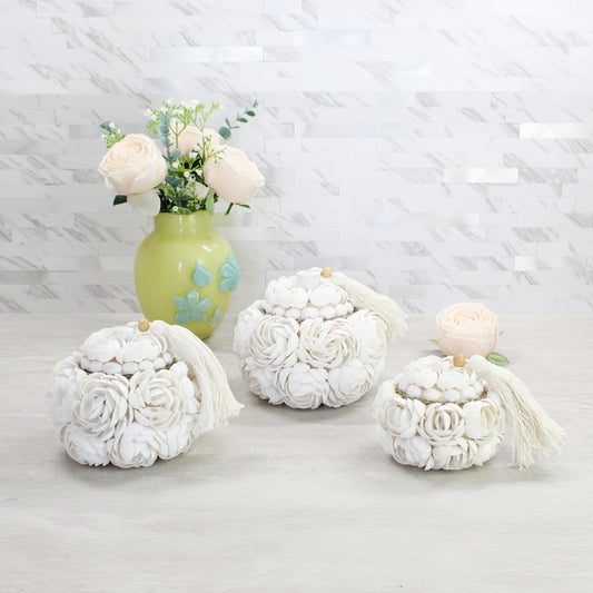 Set of three handmade seashell rose storage boxes with tassels in small, medium, and large sizes, displayed with a floral vase for coastal-inspired décor.