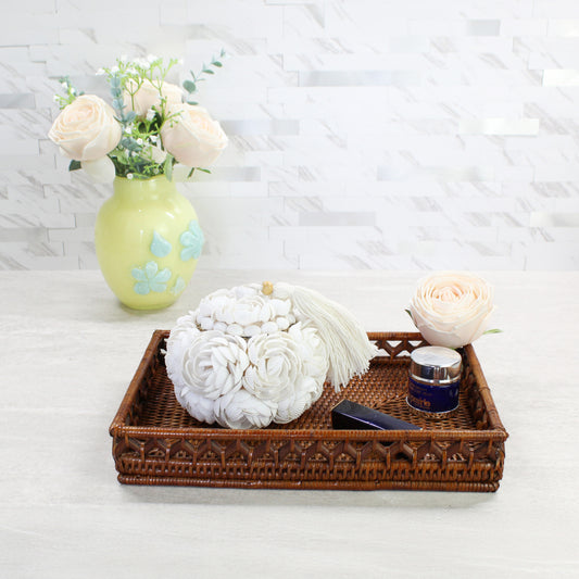 Handmade seashell rose decorative storage box with tassel styled on a woven rattan tray in a bathroom, perfect for jewelry, trinkets, or cosmetics.