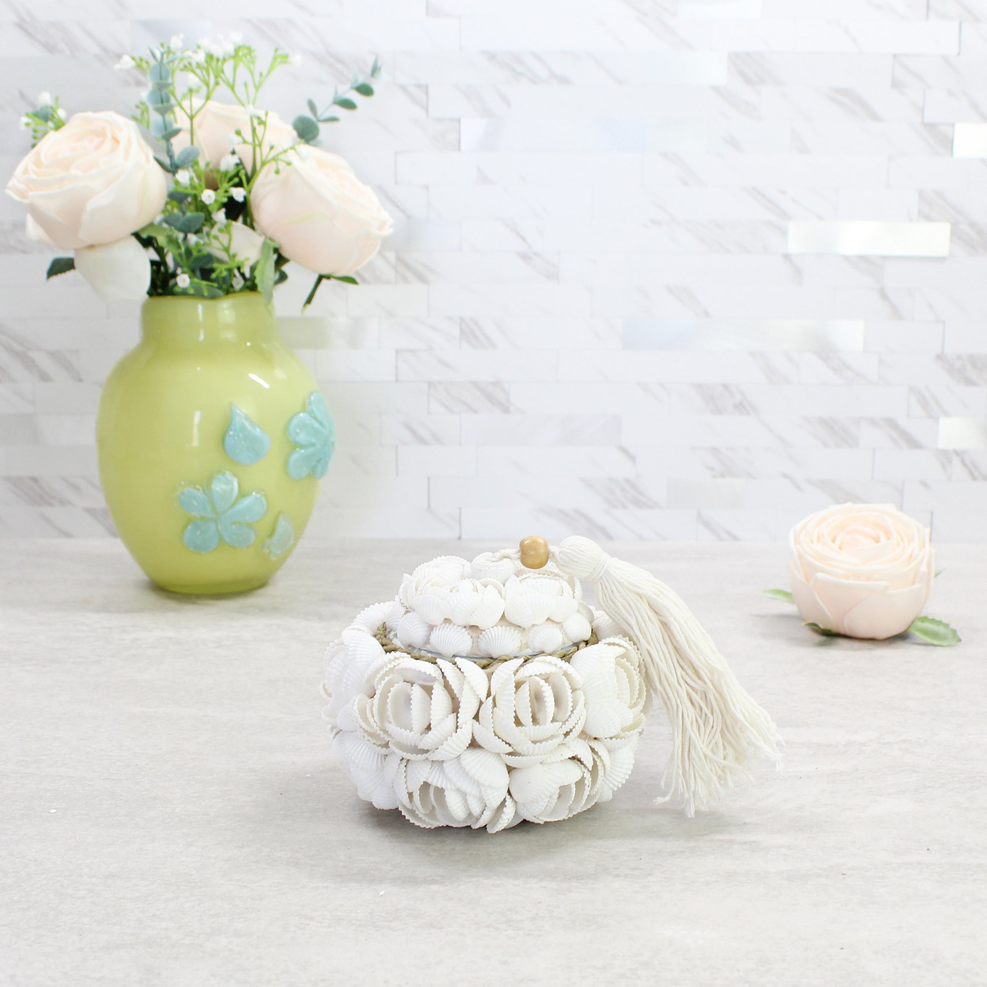 Small artisan-crafted seashell rose storage box with tassel and wood accent, handmade from natural shells for coastal-inspired decorative storage.