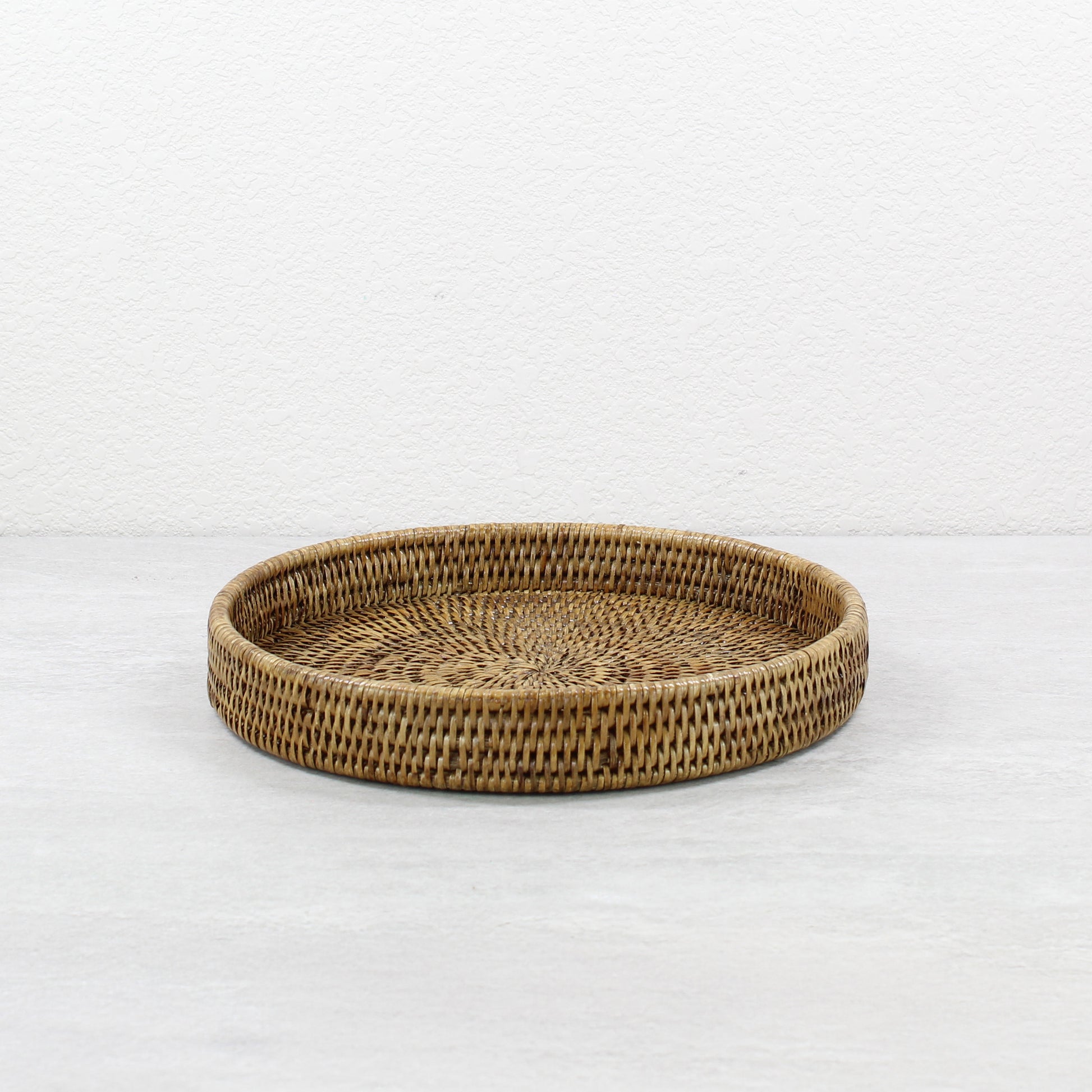 Eco Handcraft honey brown round rattan tray, 12-inch tightly woven design, ideal for serving, organizing, or styling sustainable home décor.