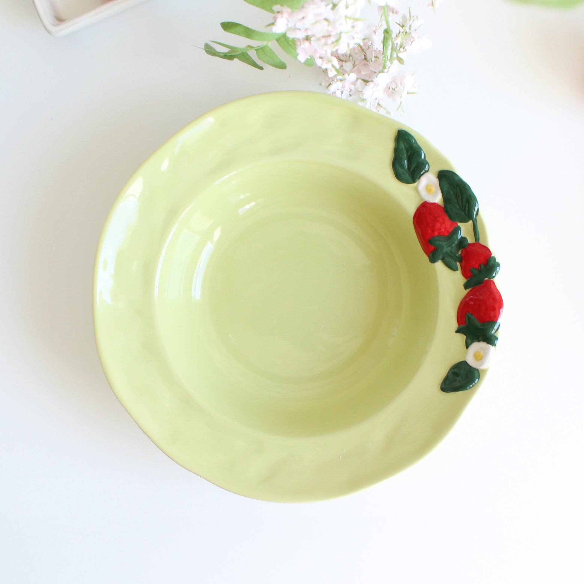 Handpainted strawberry stoneware pasta bowl with embossed fruit and floral rim, artisan green ceramic bowl