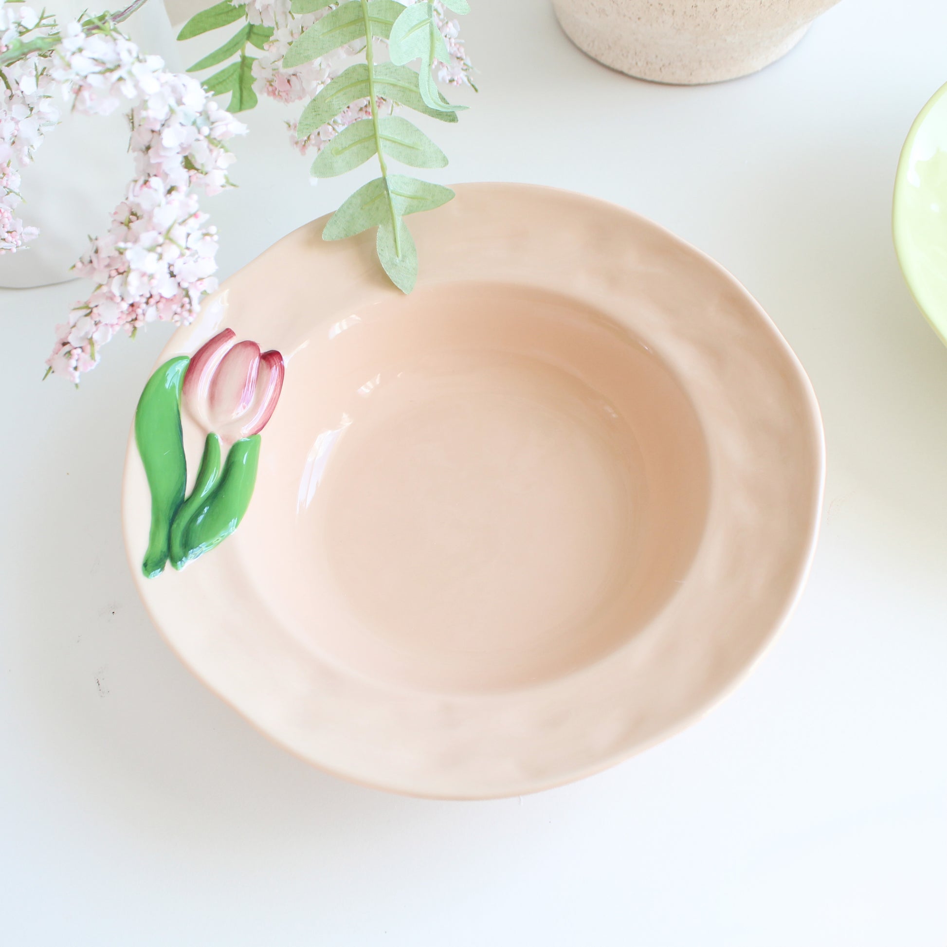 Close-up of embossed tulip detail on peach stoneware pasta bowl, handpainted ceramic dinnerware