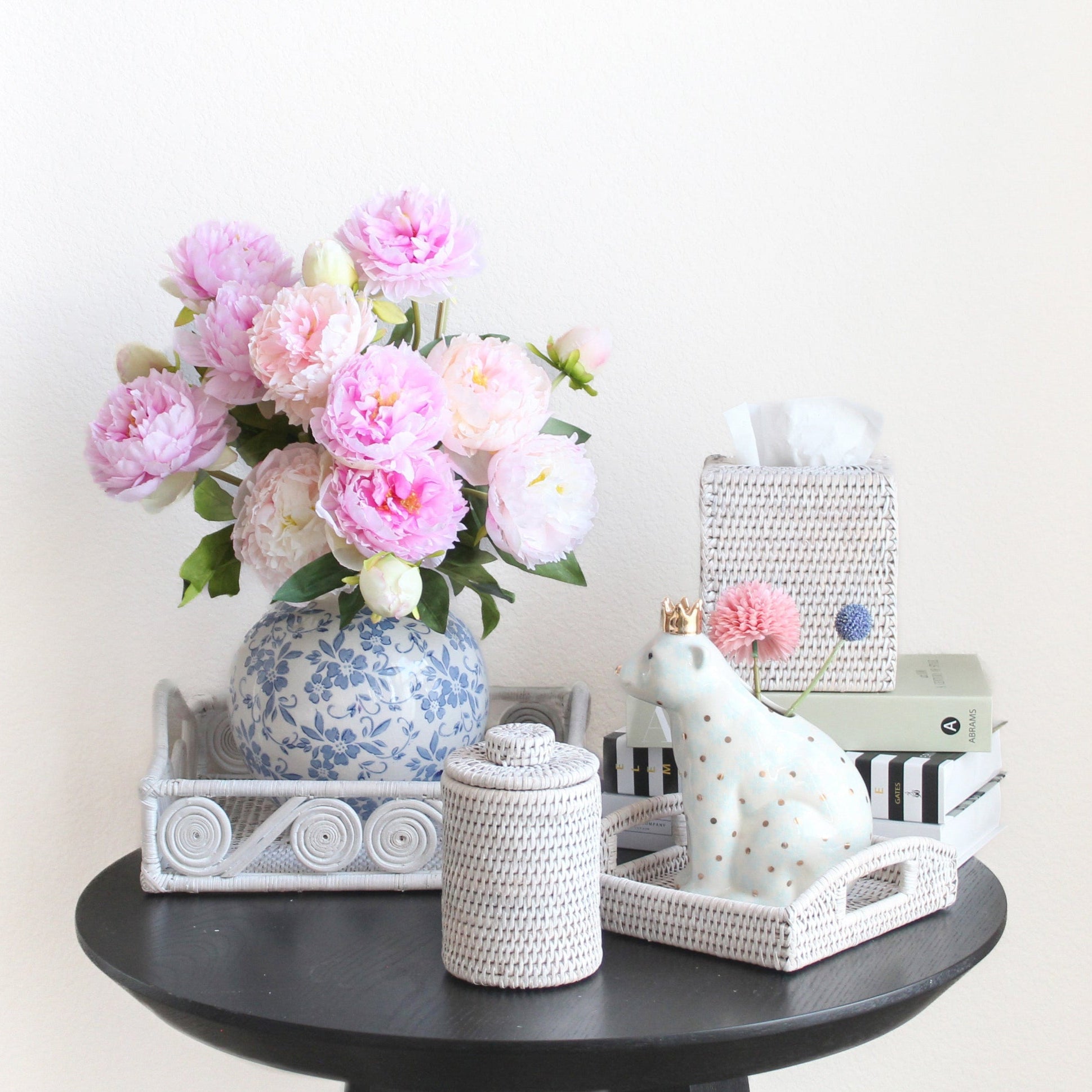 Eco Handcraft whitewash rattan canisters and trays styled with floral vase and bear decor for elegant home organization