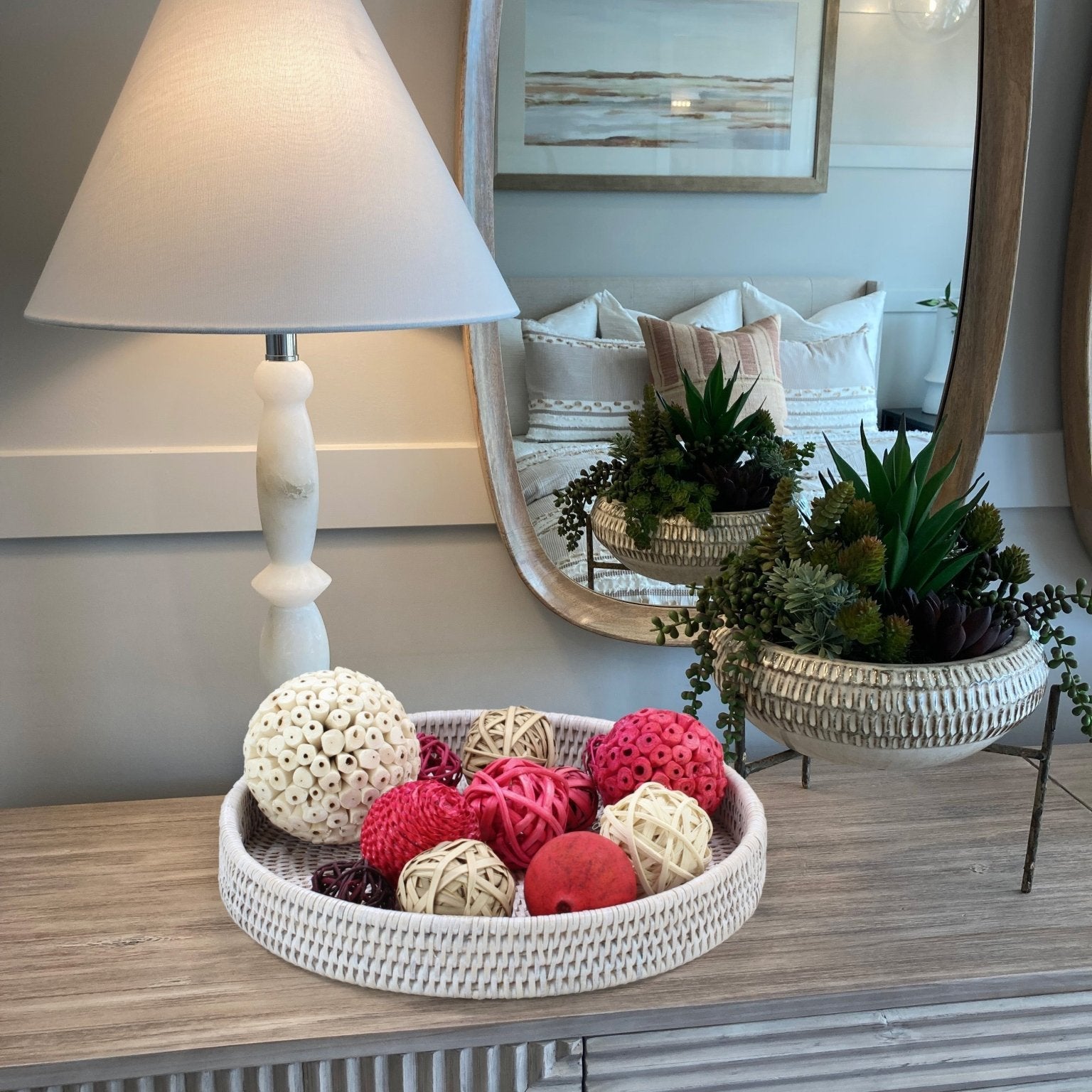 Eco-friendly handmade whitewash rattan tray styled with assorted decorative balls, artisanal centerpiece décor on a table in the bedroom.