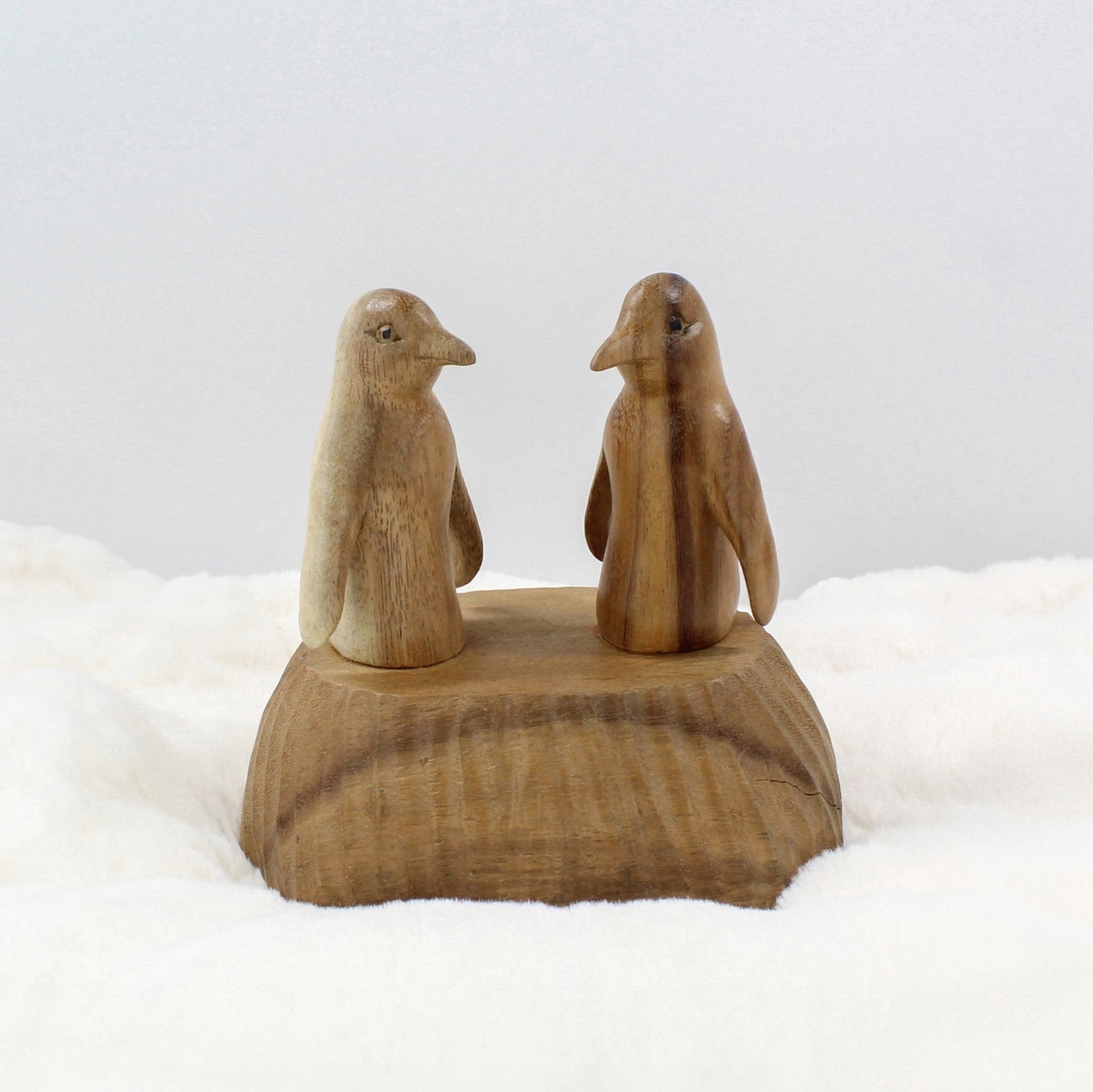Hand-carved wooden penguin sculpture set on a natural wood base, artisanal sustainable home décor.
